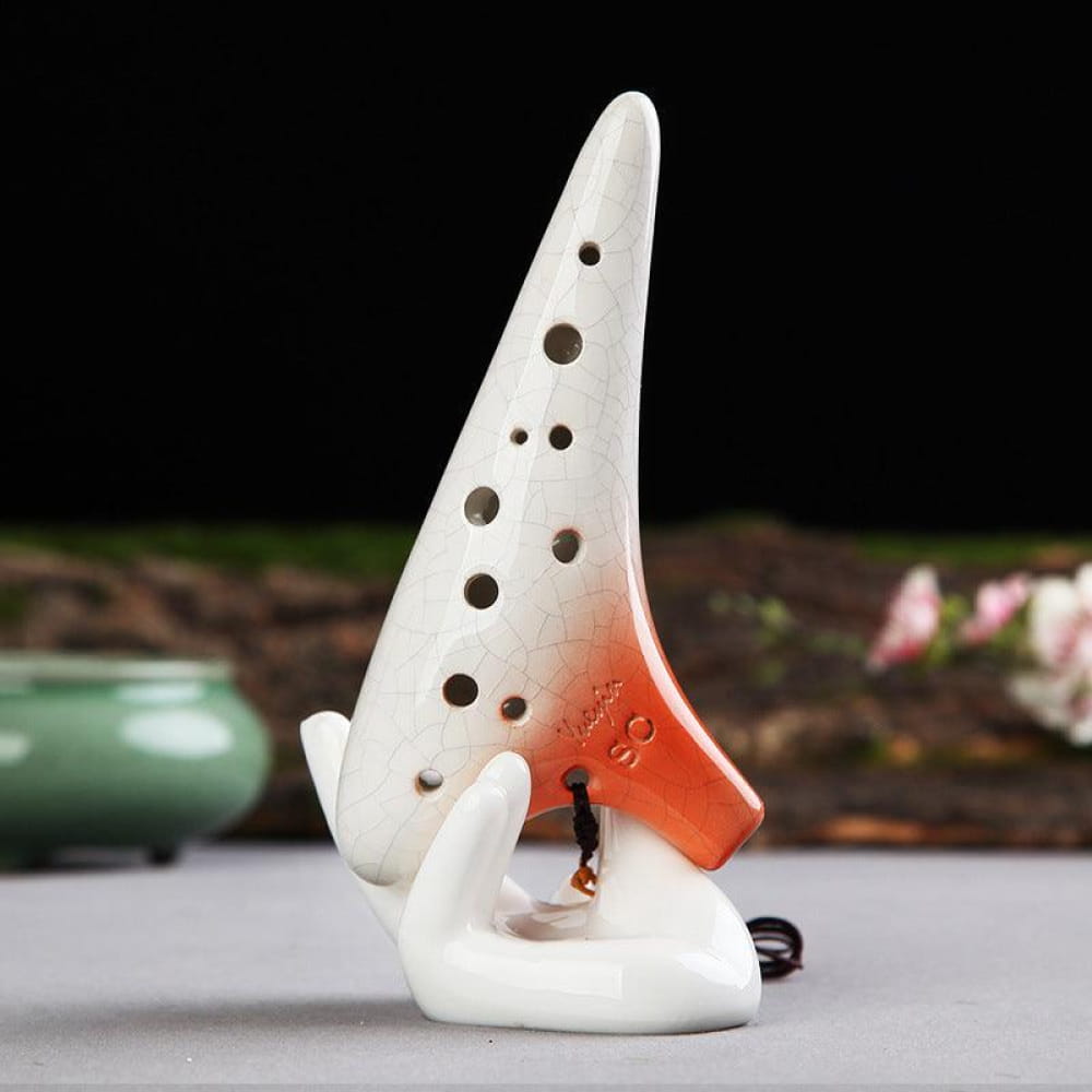 White ceramic 12 hole soprano ocarina with orange-red accents and finger holes