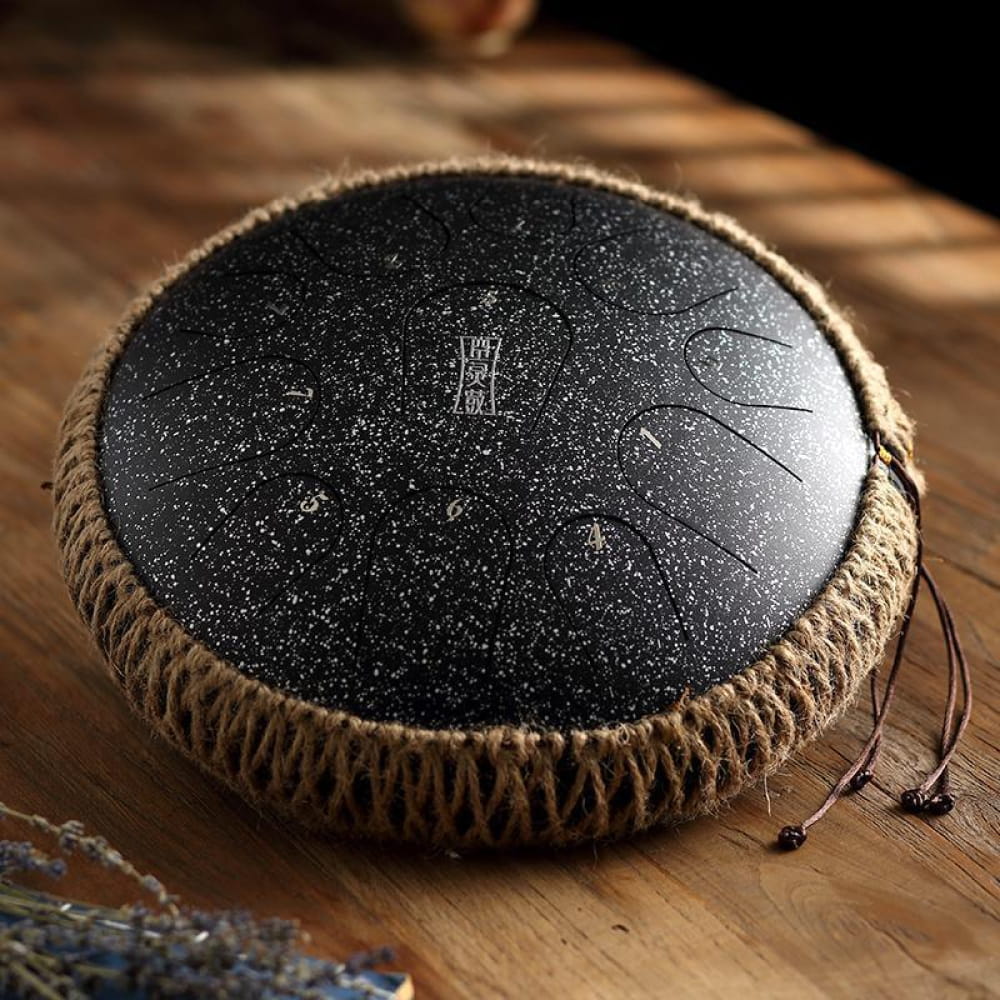 Round black Titanium Steel Tongue Drum with decorative markings and rope-wrapped edges