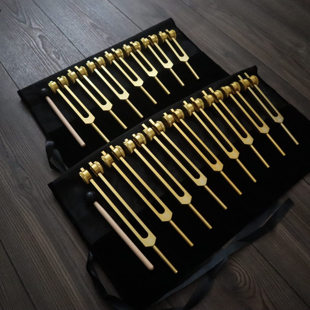 Collection of golden tuning forks in rows on black fabric for chakra healing set