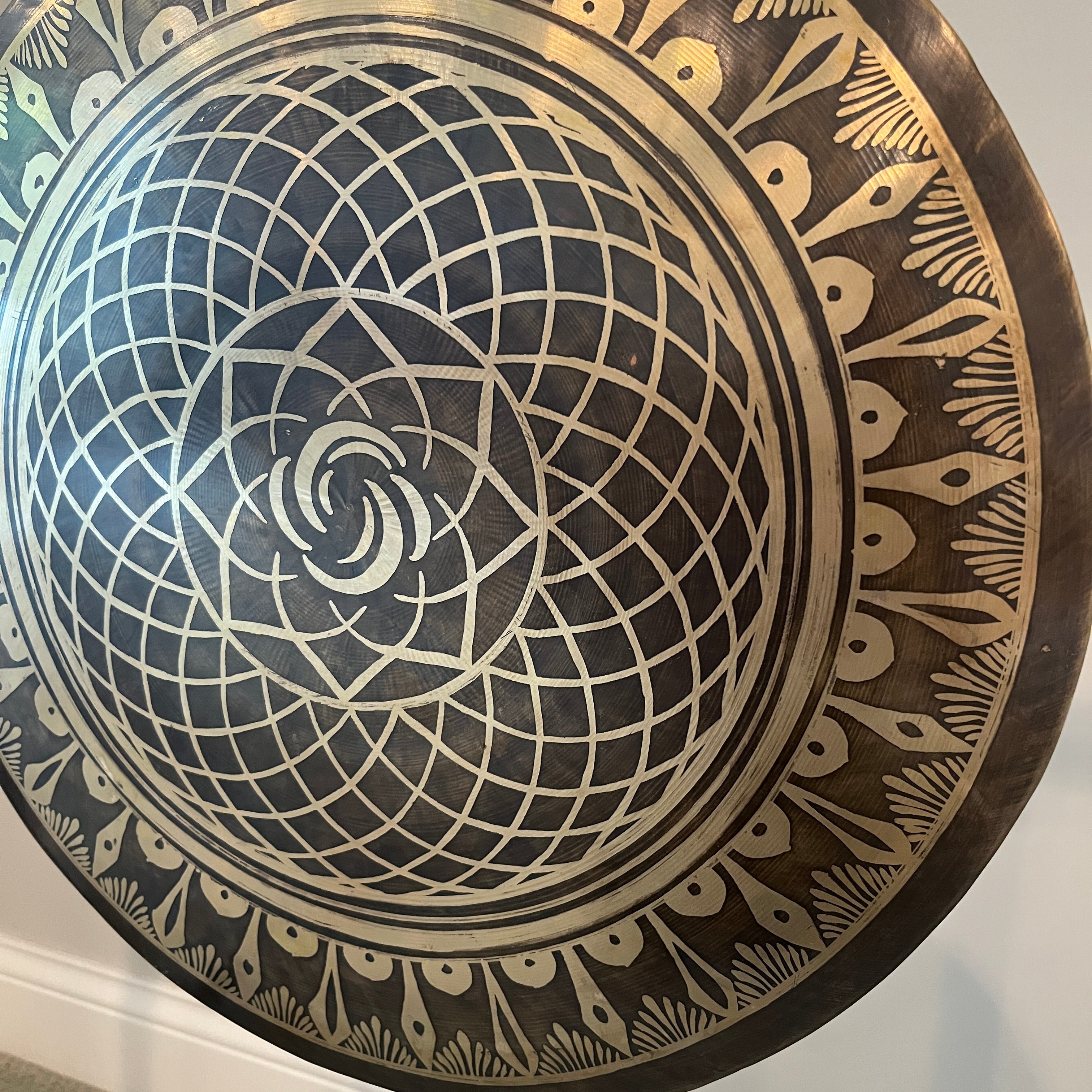Circular decorative plate featuring intricate black and white geometric spiral pattern