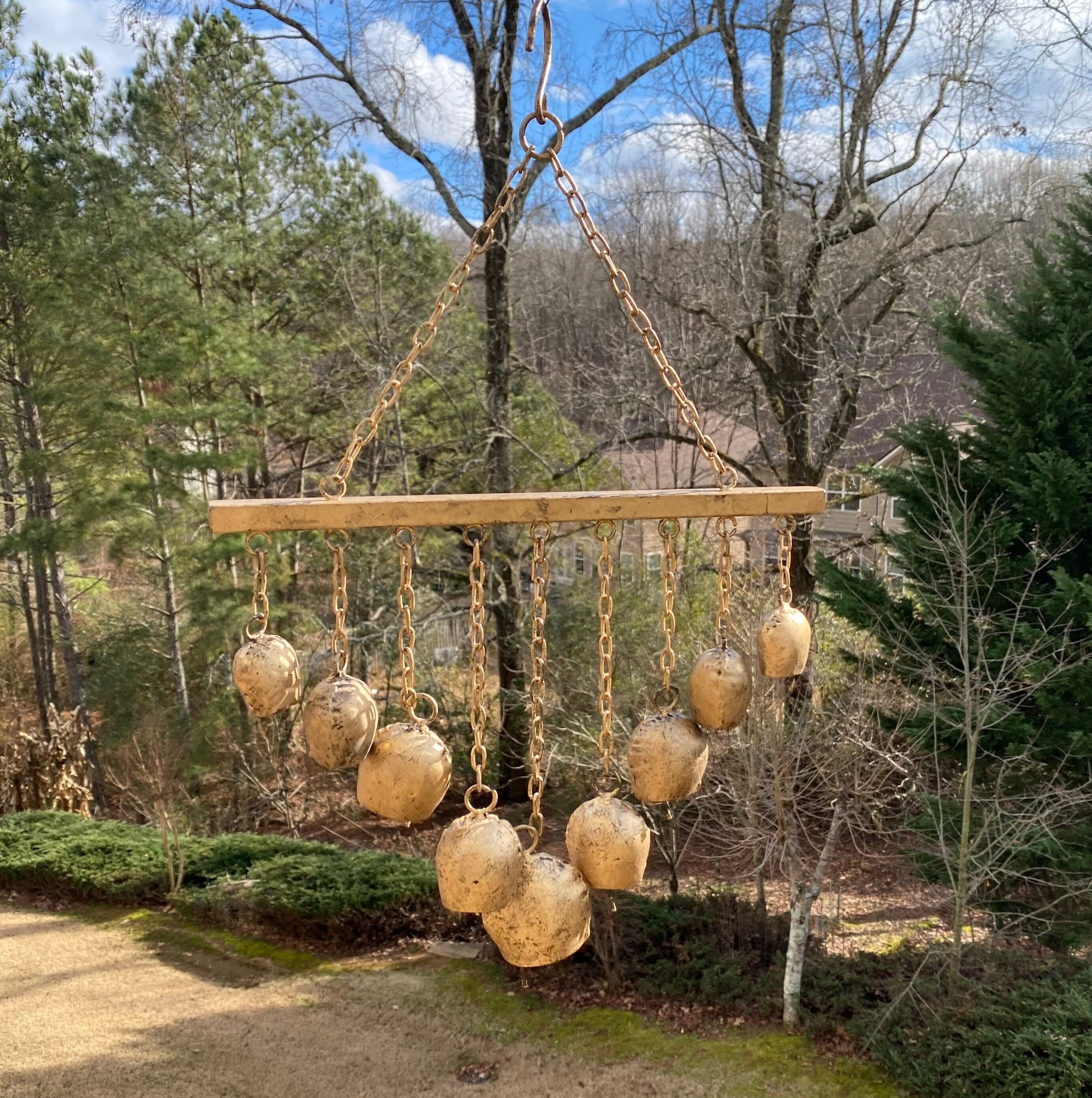 Wooden chandelier with frosted glass globes hanging from rope above rustic wind chimes