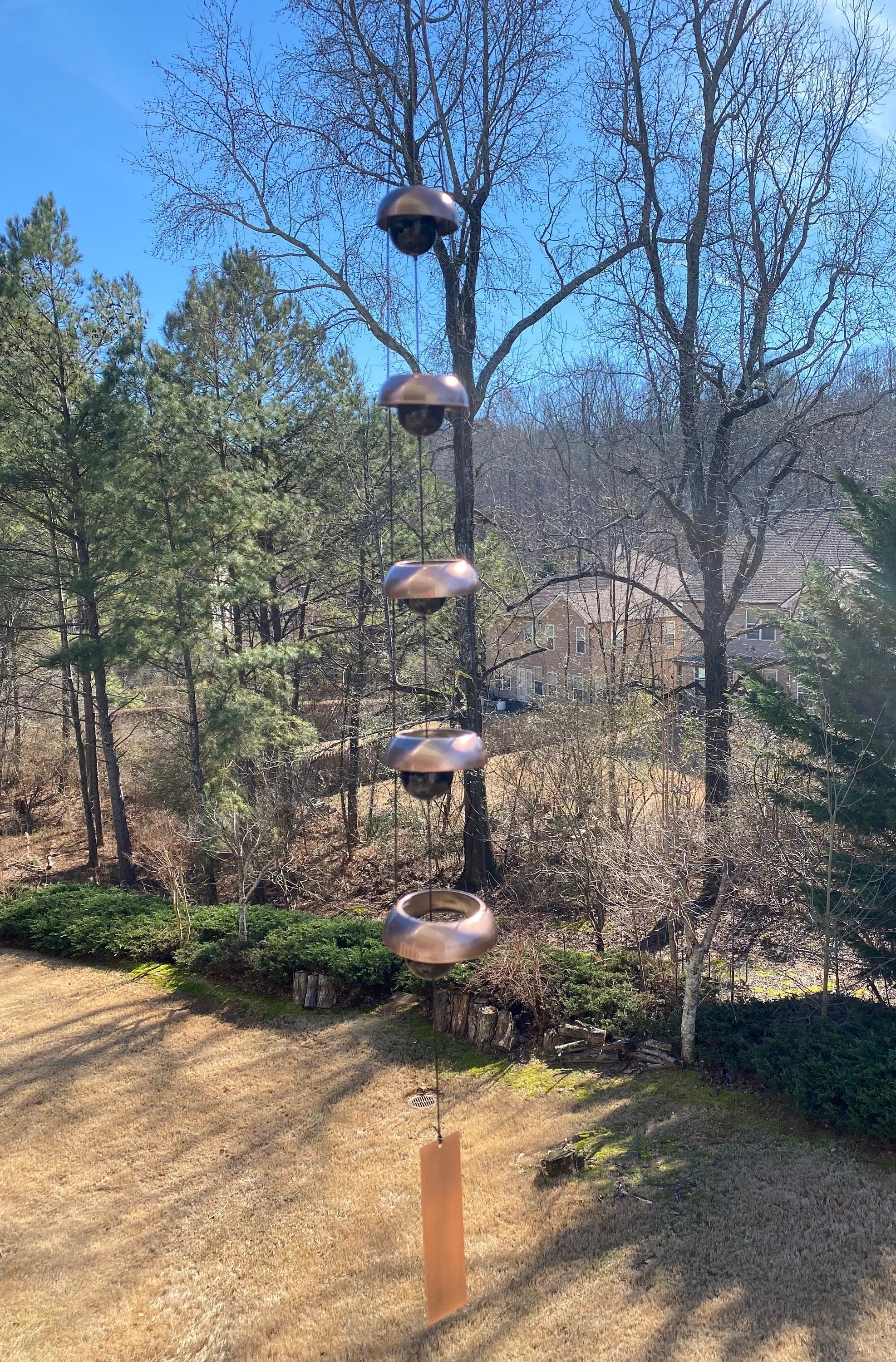 Multi-tiered bird feeder pole with stacked platforms near 37 Copper Wind Chime with 5 Bells
