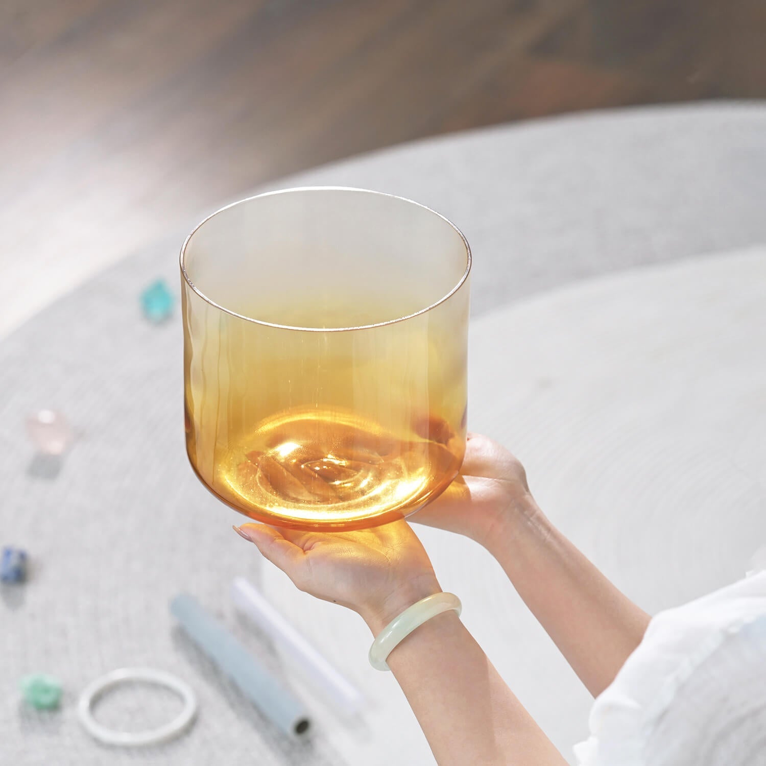 Glass of golden liquid held above a 6-7 inch Quartz Crystal Singing Bowl for meditation