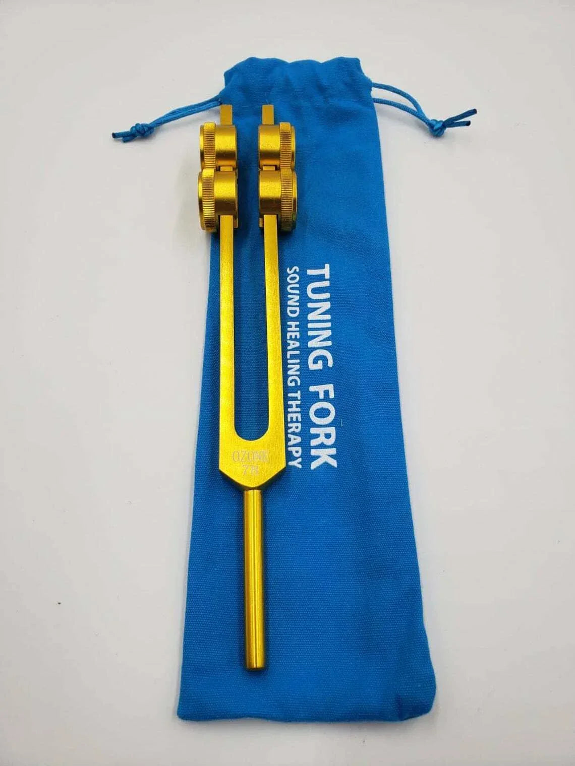 Gold-colored 78 Hz tuning fork with blue storage pouch for healing and activator set