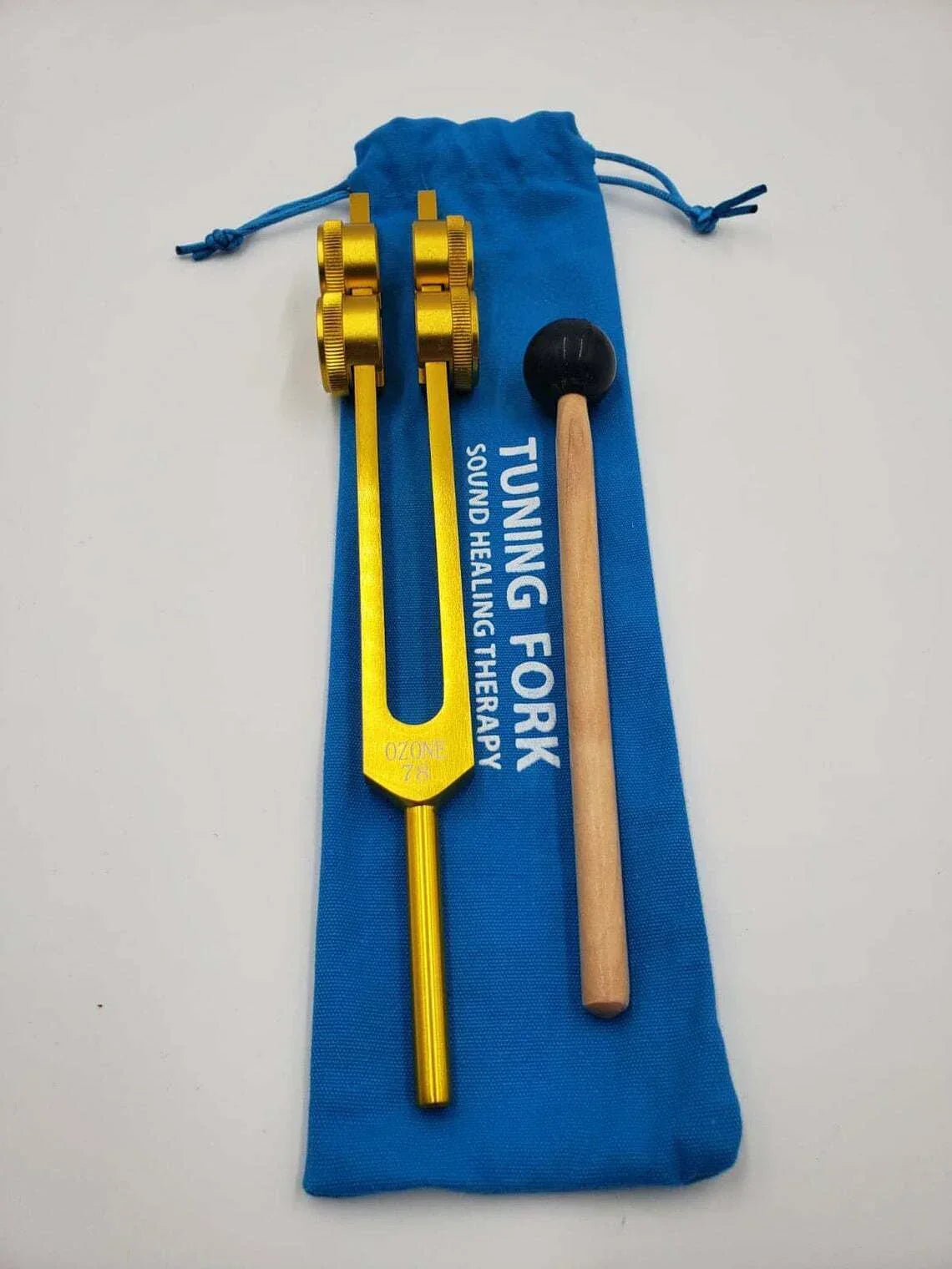 Gold tuning fork and wooden mallet in blue pouch for 78 Hz healing therapy