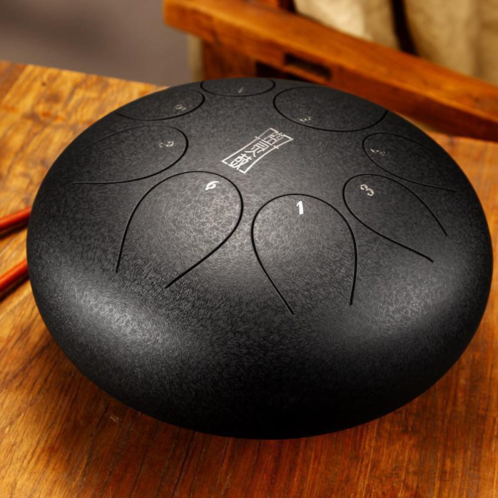 Black steel tongue drum with circular markings on 8-Tone D Key model, 12 inches round