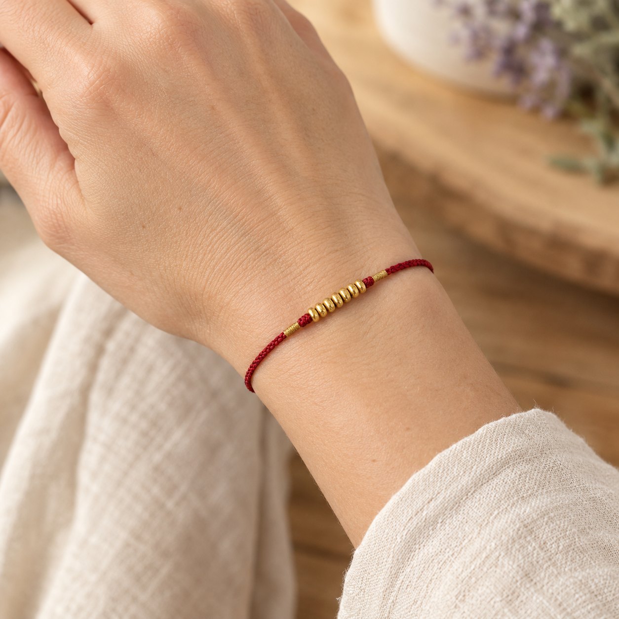 999 Gold Ultra-Thin Braided Red String Bracelet, worn on the wrist by a woman