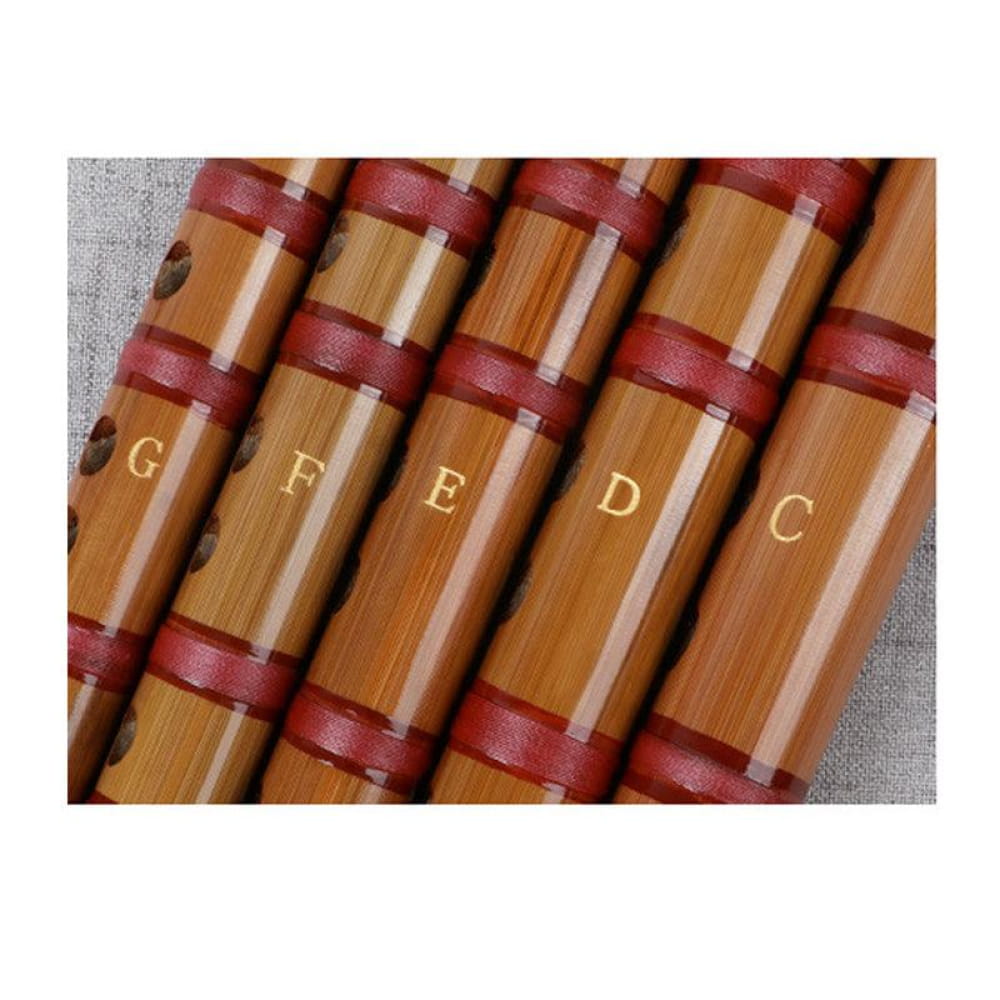 Wooden pan flute pipes with red bindings and engraved letters on a Bamboo Dizi Flute