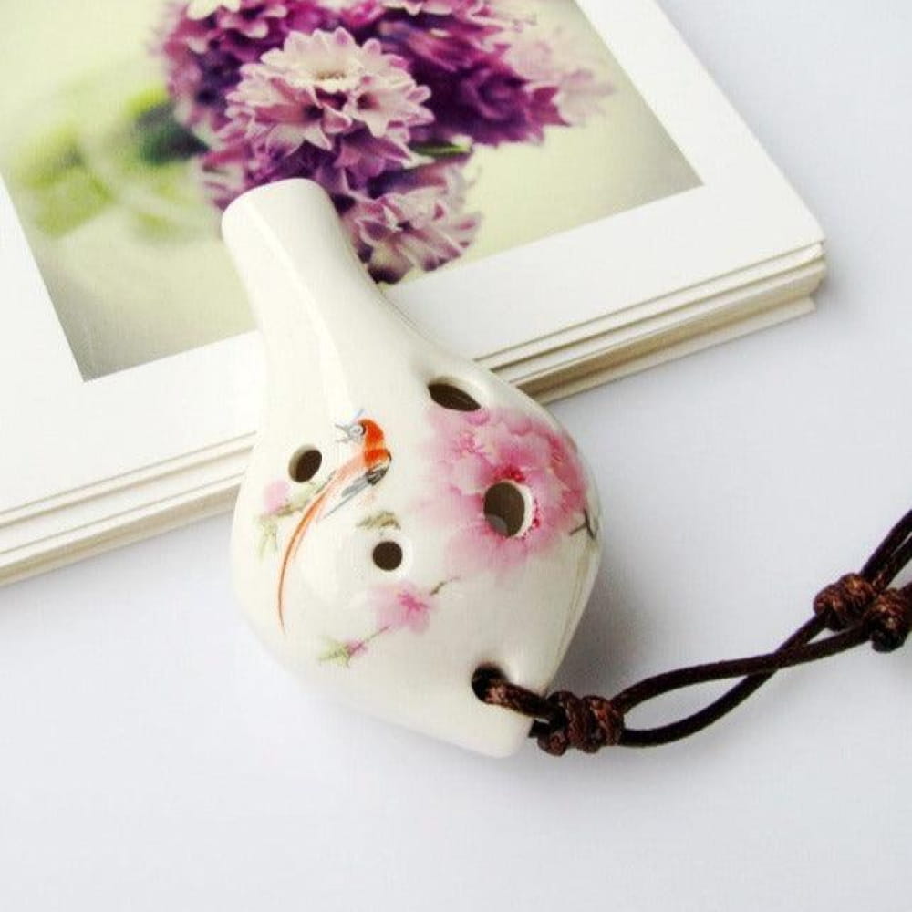 White ceramic ocarina with pink floral designs and brown cord for beginners