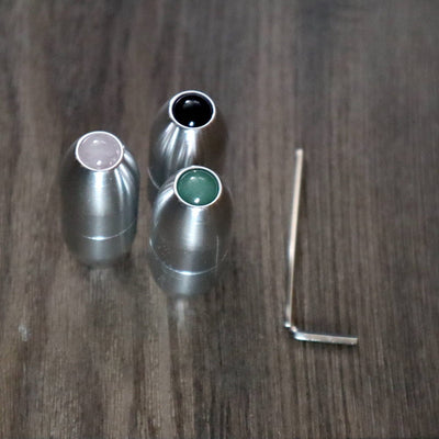 Three metallic bullet-shaped containers with colored tops and an L-shaped tool for massage