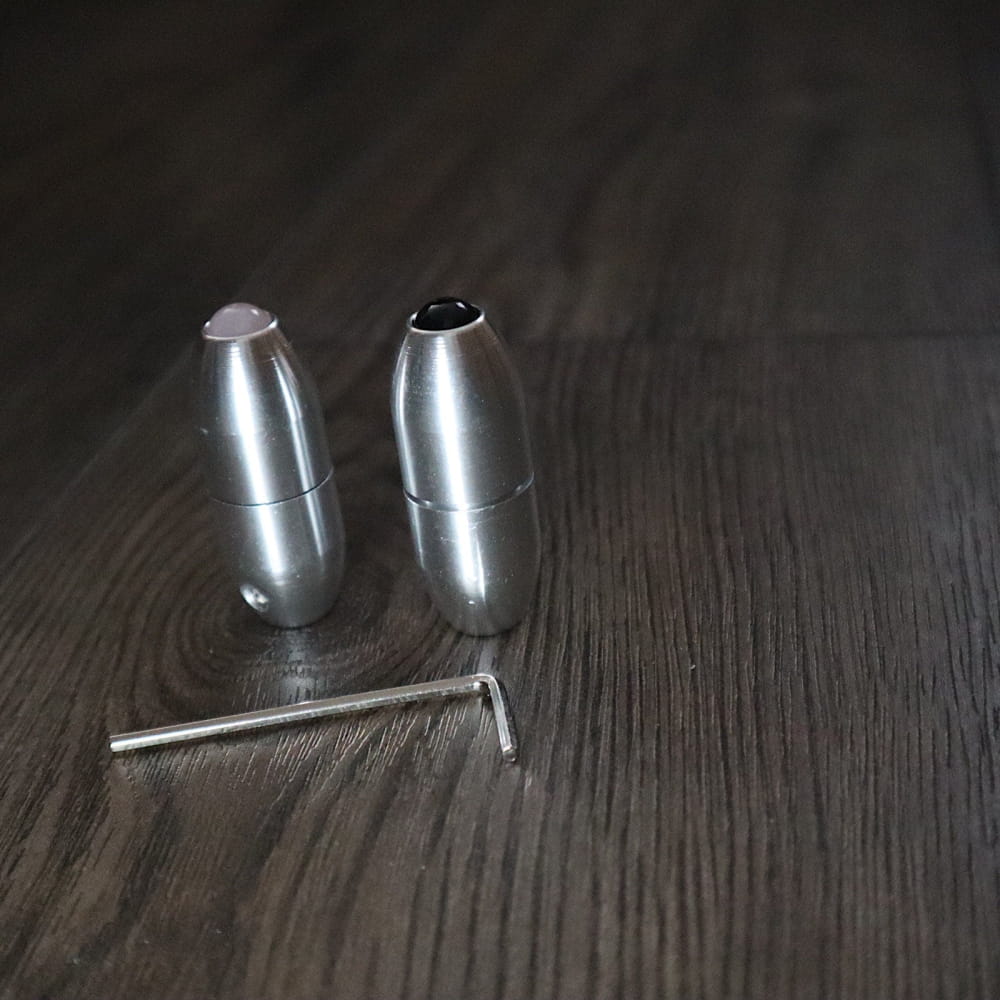 Two metallic bullet-shaped salt and pepper shakers with serving tool for dining