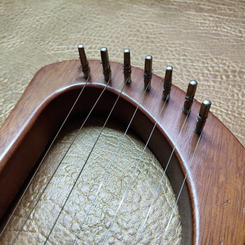 Curved wooden bridge of Lyre Harp with metal tuning pegs and rivets showcased