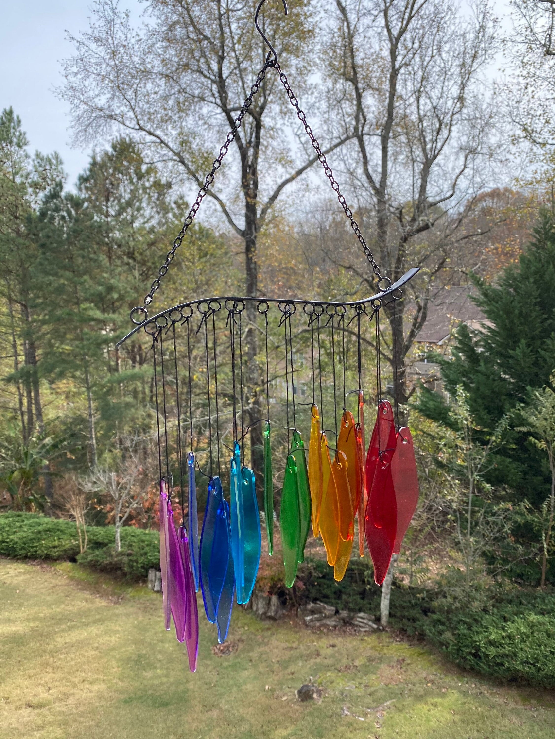 Rainbow Glass Wind Chimes hanging from a curved metal branch in vibrant colors