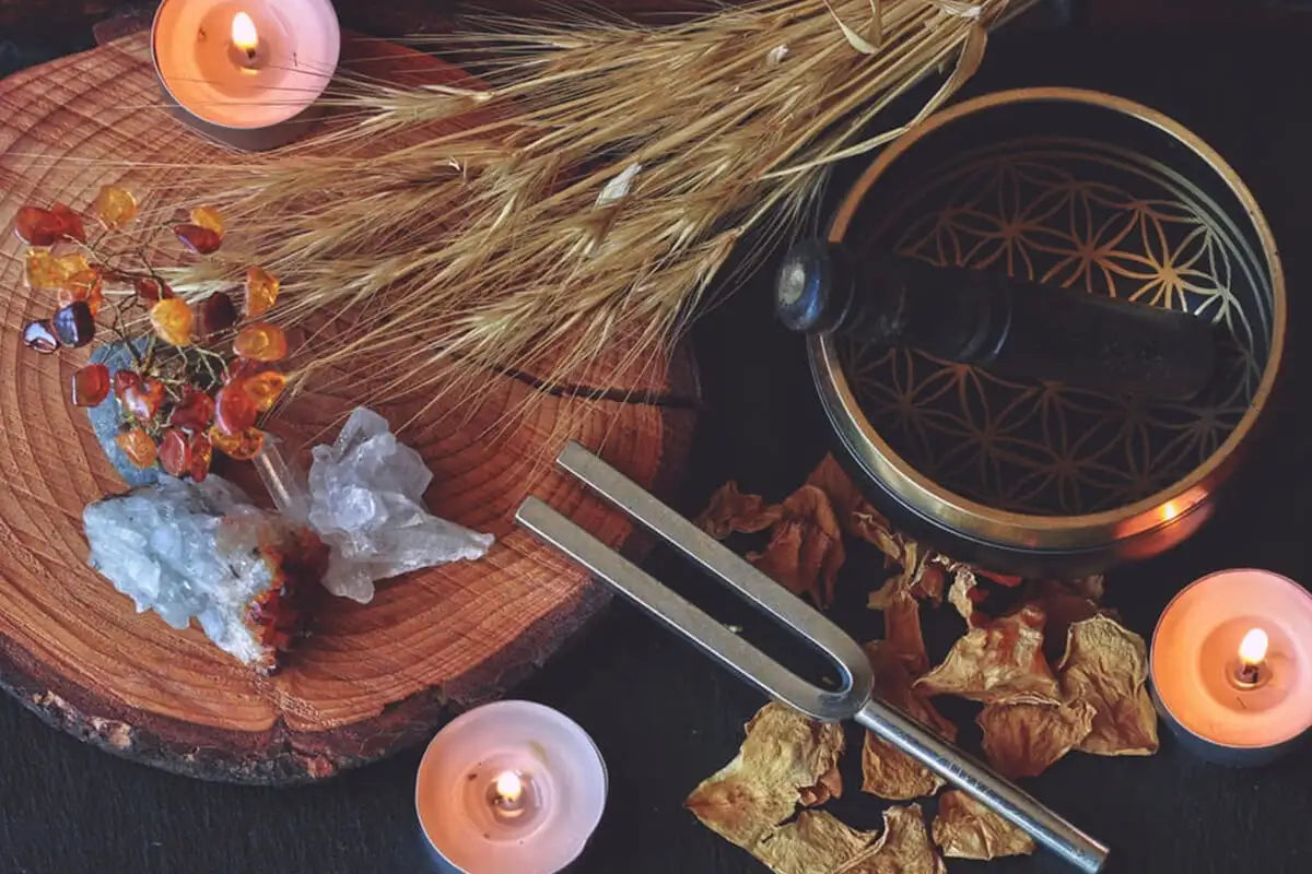 Gold-toned tibetan singing bowl with intricate geometric etchings and a dark wooden mallet resting inside.