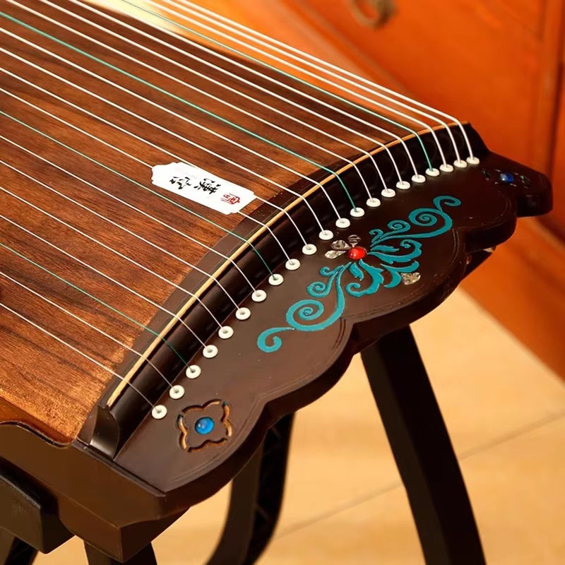 Traditional Chinese Guzheng with turquoise flourishes on a black bridge, 21 strings