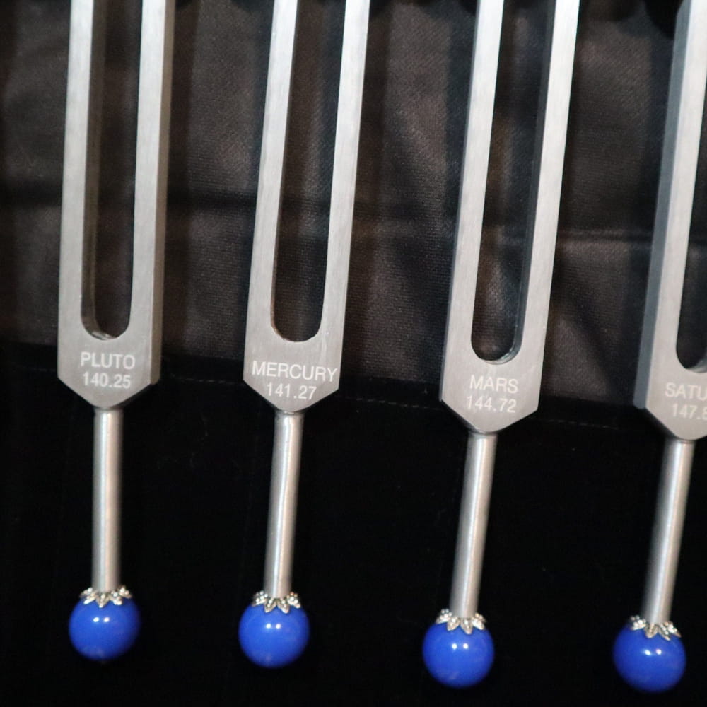 Tuning forks with blue tips labeled with planet names for astrology and sound healing