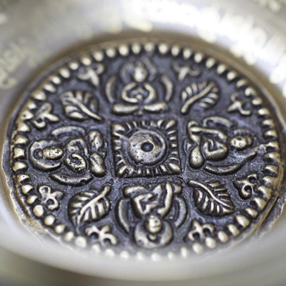 Ornate silver medallion with floral and geometric patterns on Himalayan Singing Bowl