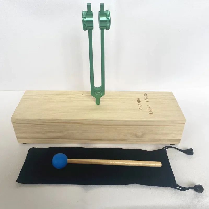 Green tuning fork on wooden resonance box with mallet for Heart Chakra healing