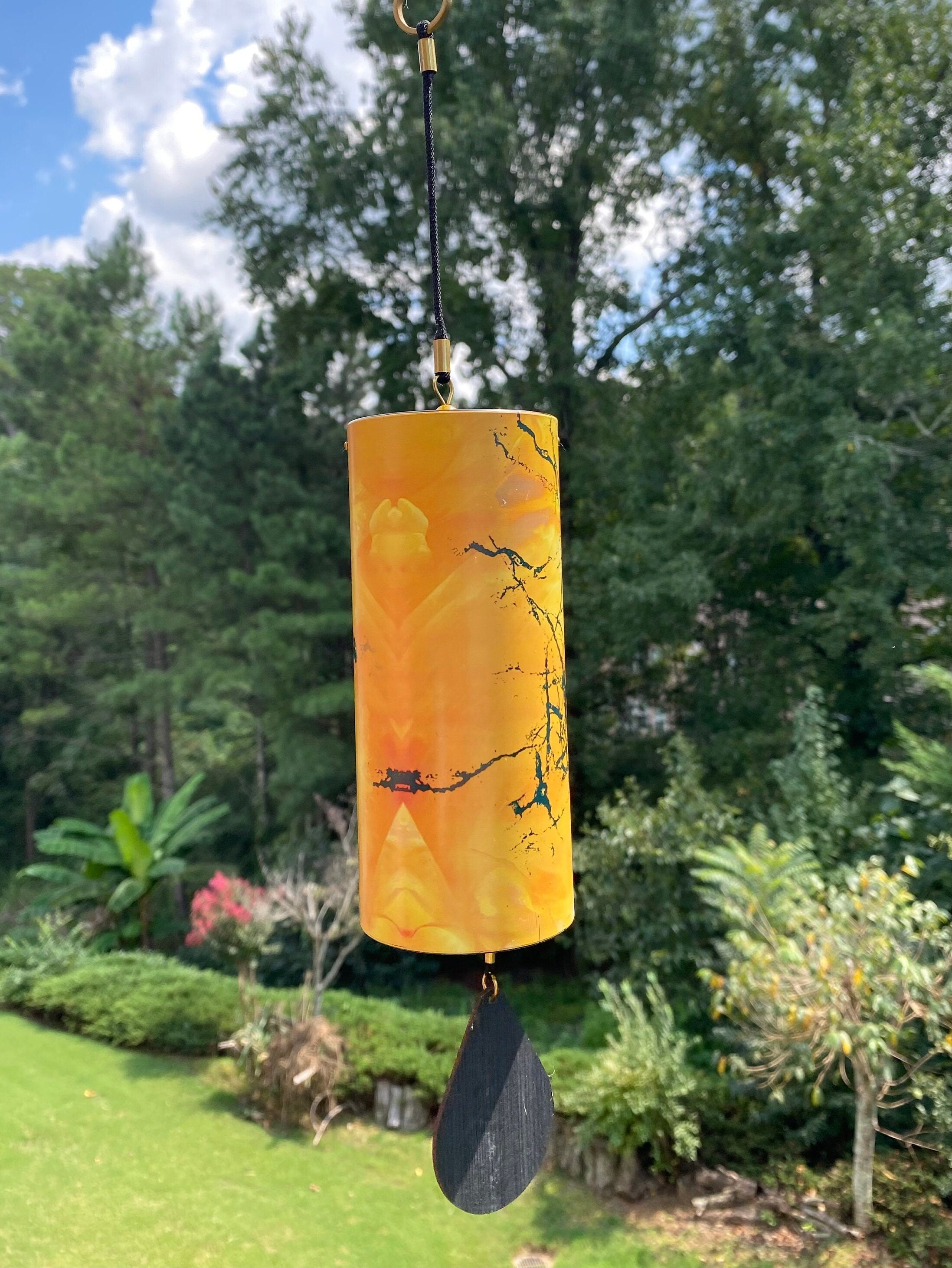 Cylindrical orange wind chime with decorative branch designs for home and garden