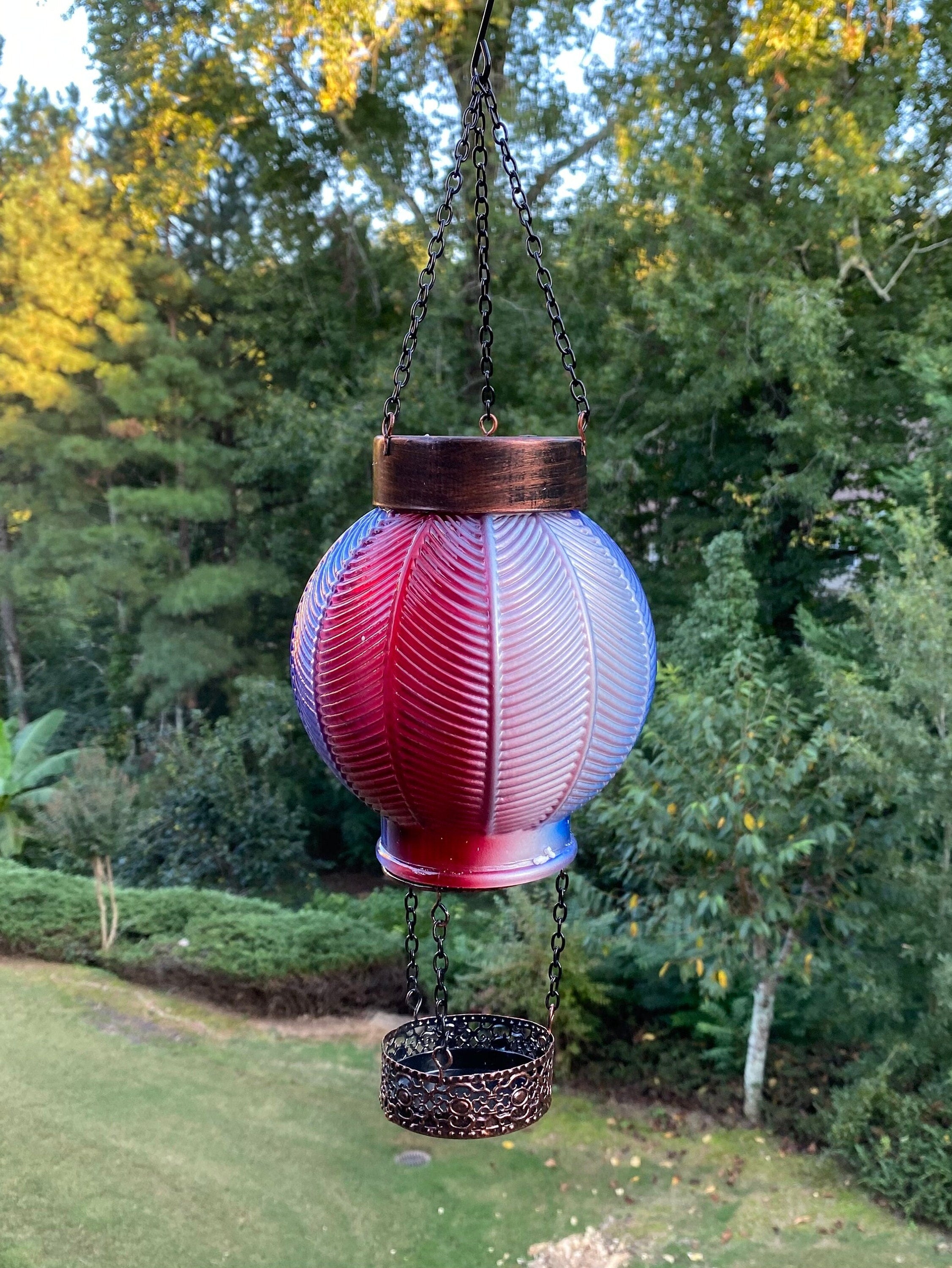 Red and white striped glass lantern hanging from chain for outdoor decor