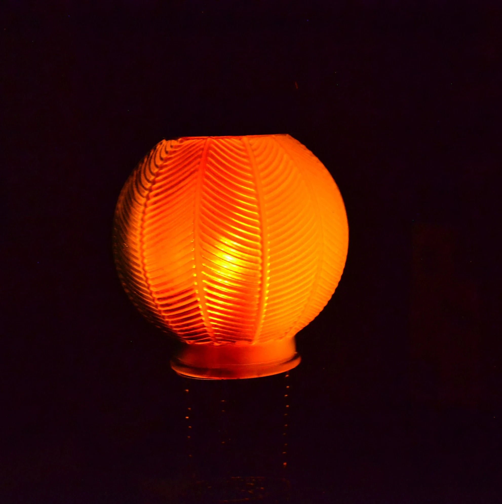 Glowing orange spherical lamp with textured pattern in solar flickering flame lantern