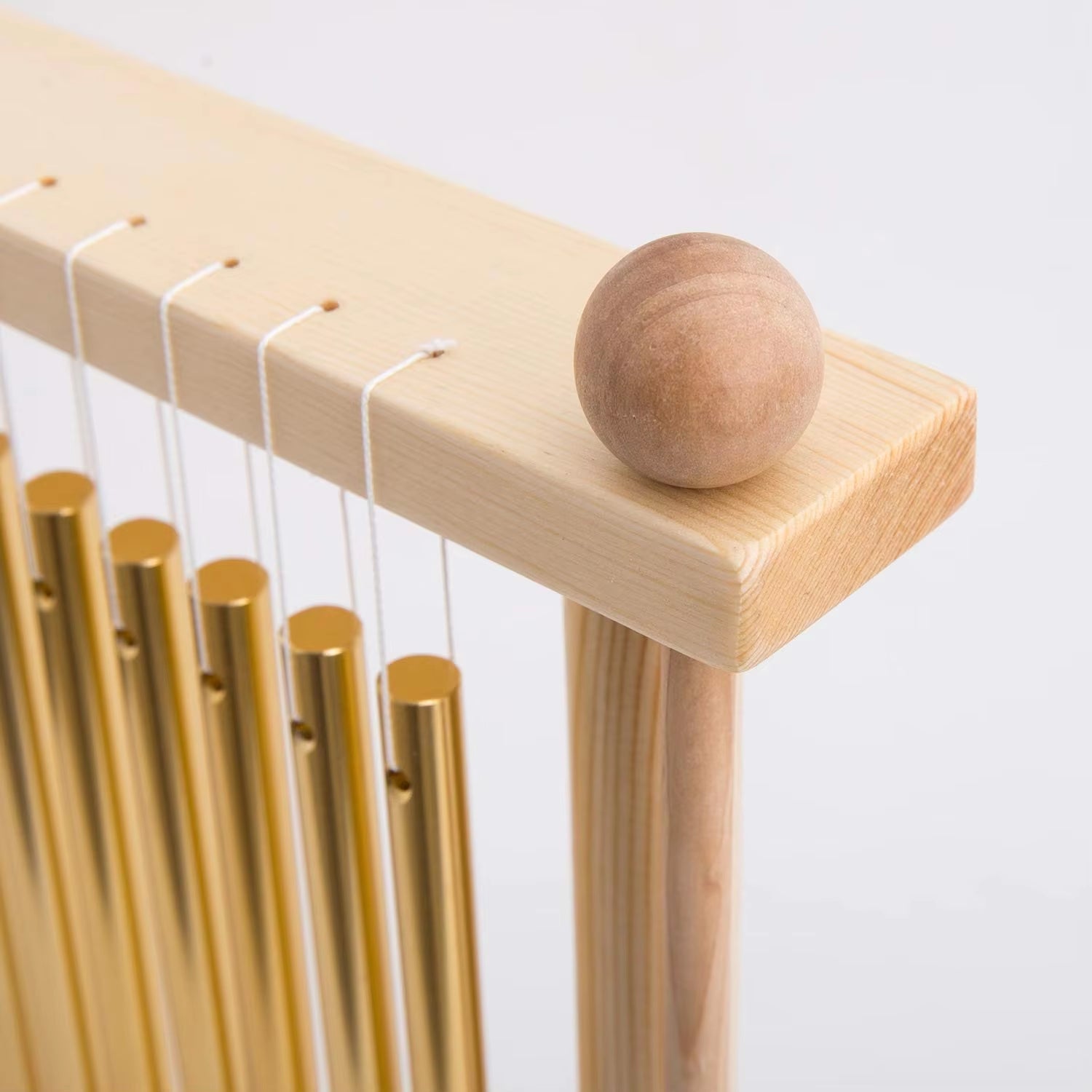 Wooden ball on light ledge near golden chimes of 20-Bar Swing Chimes with Mallet Gold