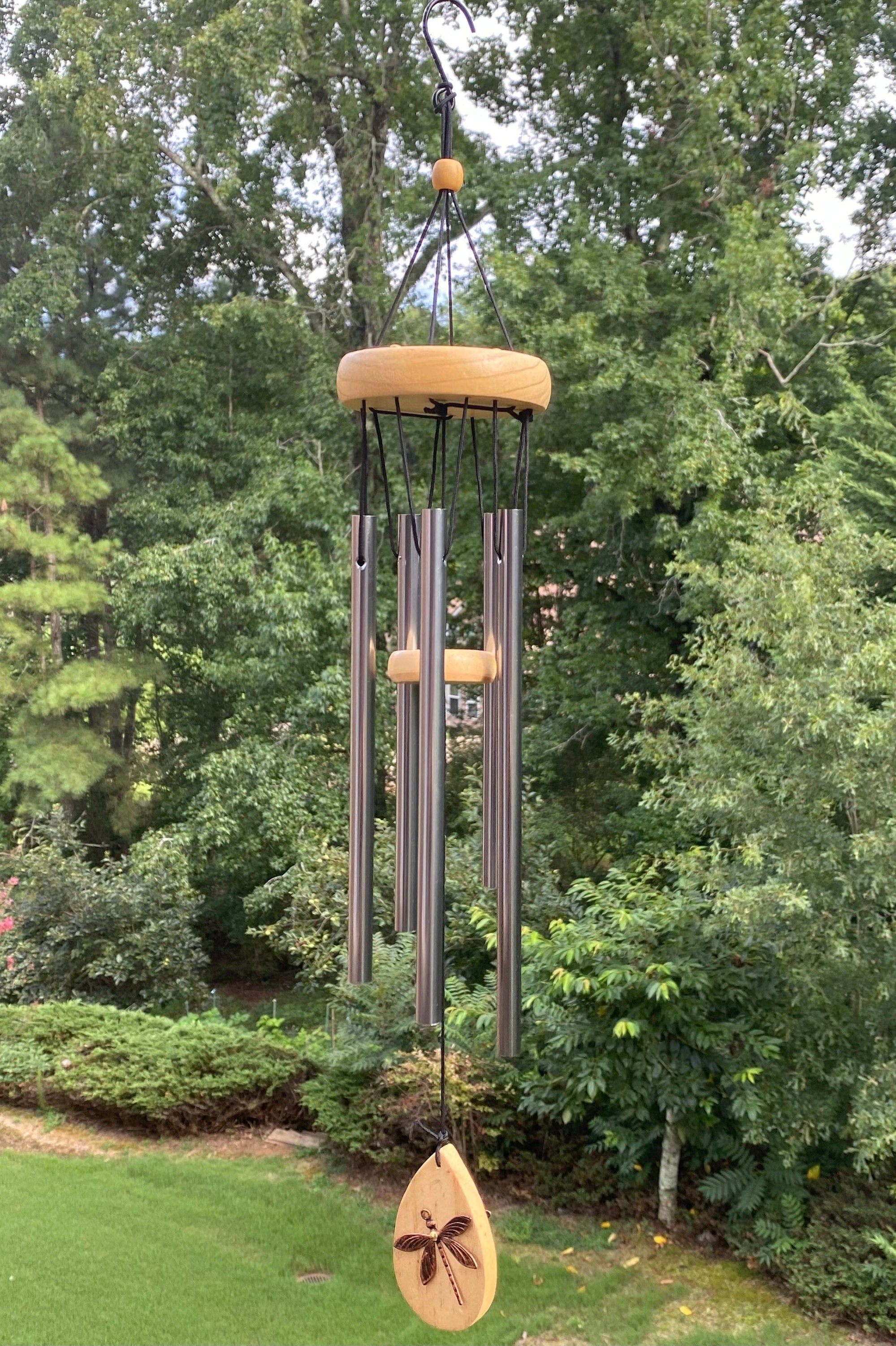 Wind chimes with metal tubes and wooden accents in a garden setting for sympathy gifts