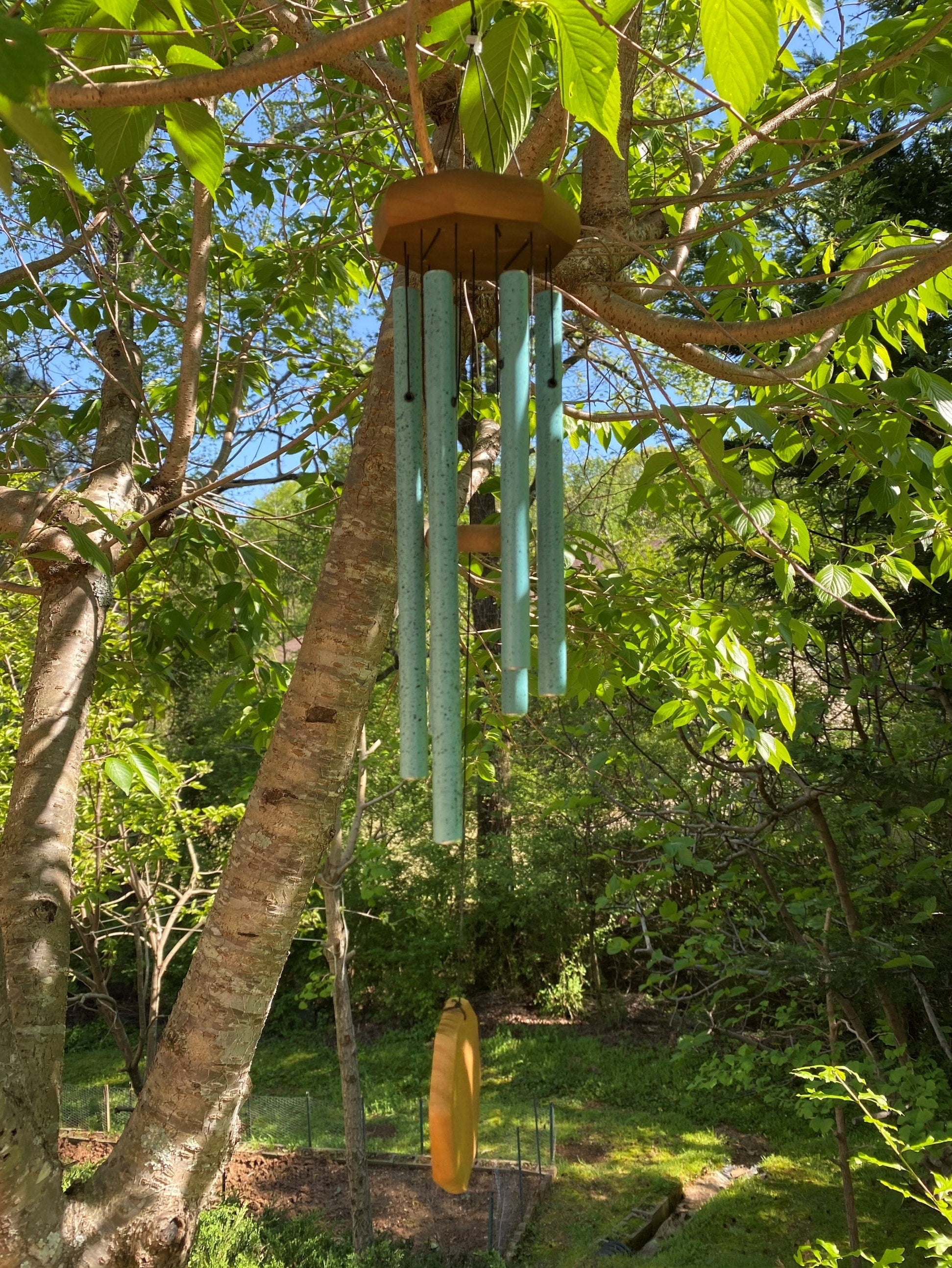 Turquoise wind chimes with metallic tubes hanging from wooden disk for memorial use