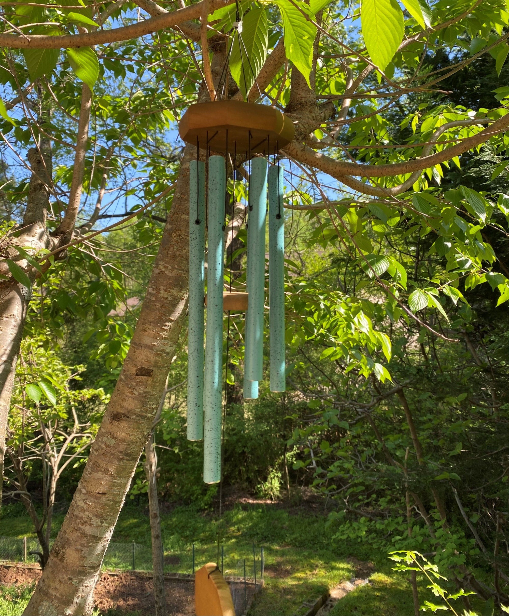 Turquoise wind chimes hanging from a wooden disc in a Memorial Copper design