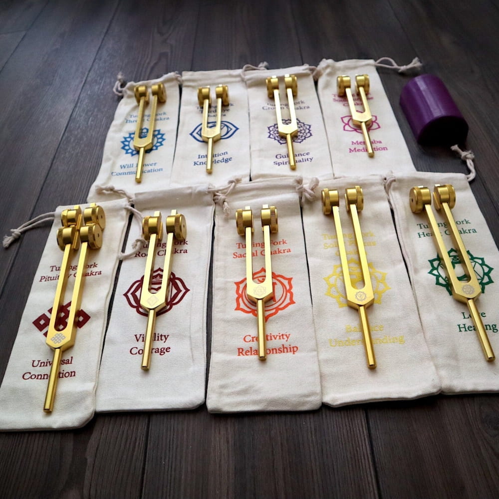 Collection of golden tuning forks in labeled pouches for chakra healing set