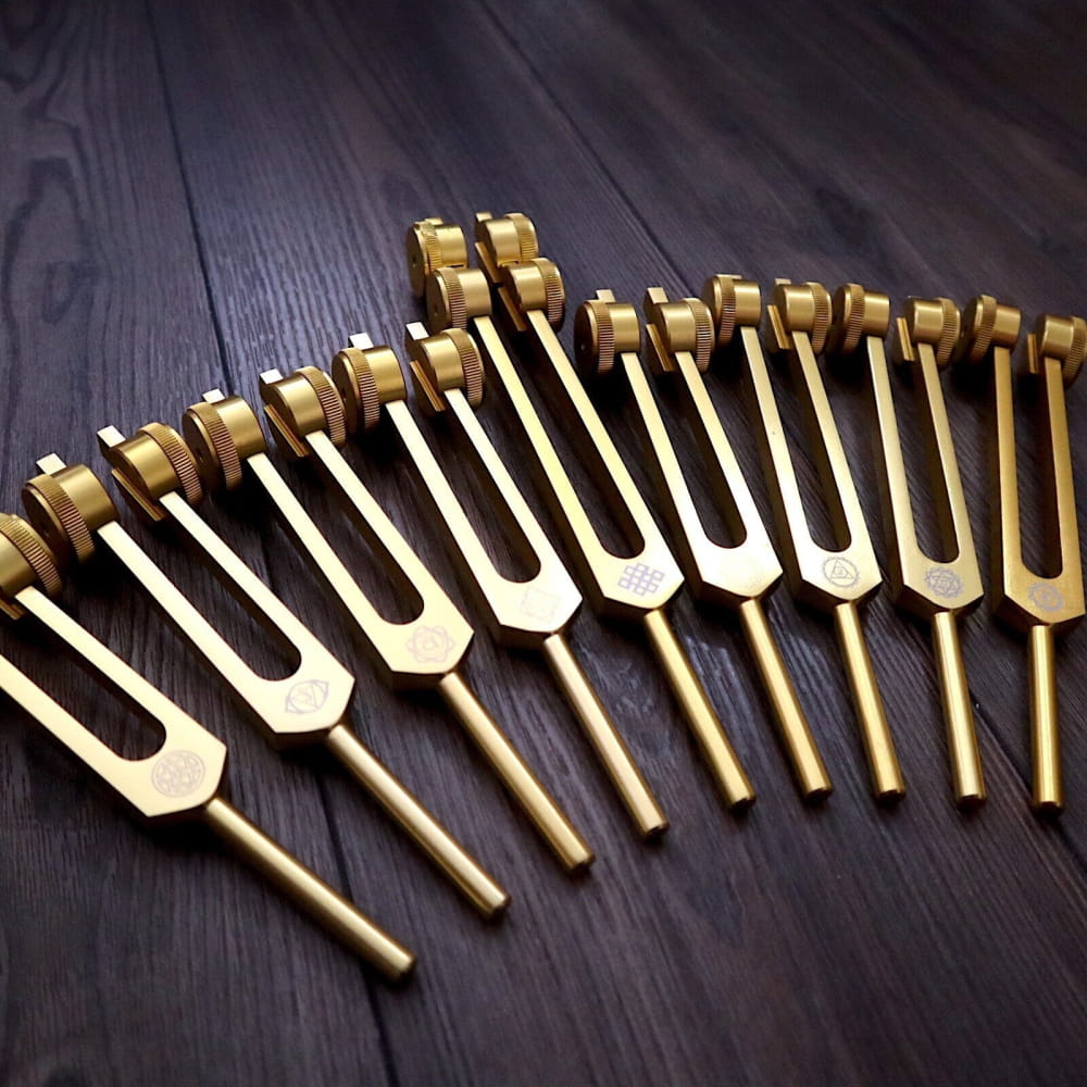 Row of golden tuning forks in a curved line for chakra healing and sound therapy