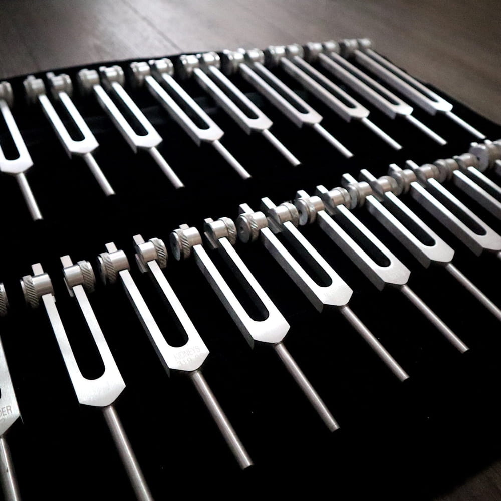 Collection of gold and silver tuning forks in parallel rows for sound healing