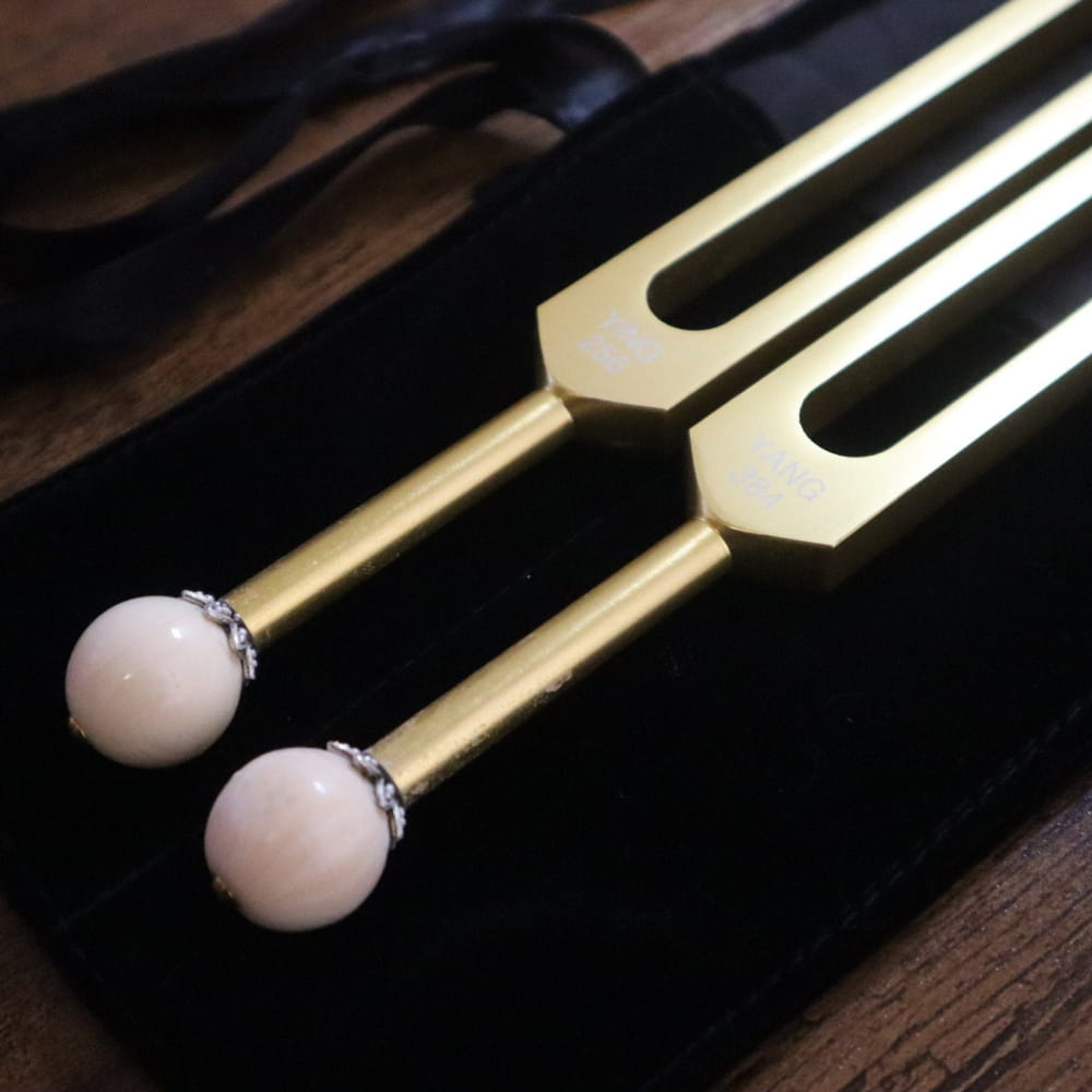 Two tuning forks with white ends for Chakra healing in a gold Yin Yang set