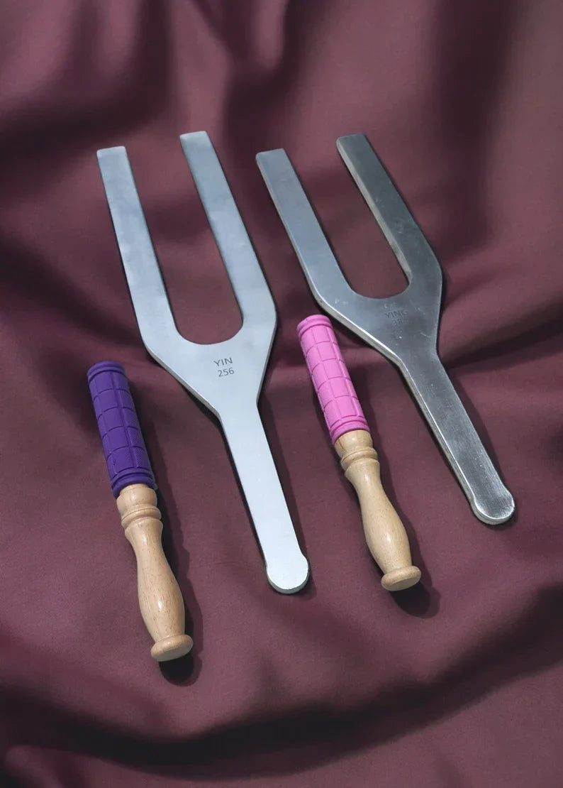 Four tuning forks with wooden handles wrapped in colorful thread for healing therapy