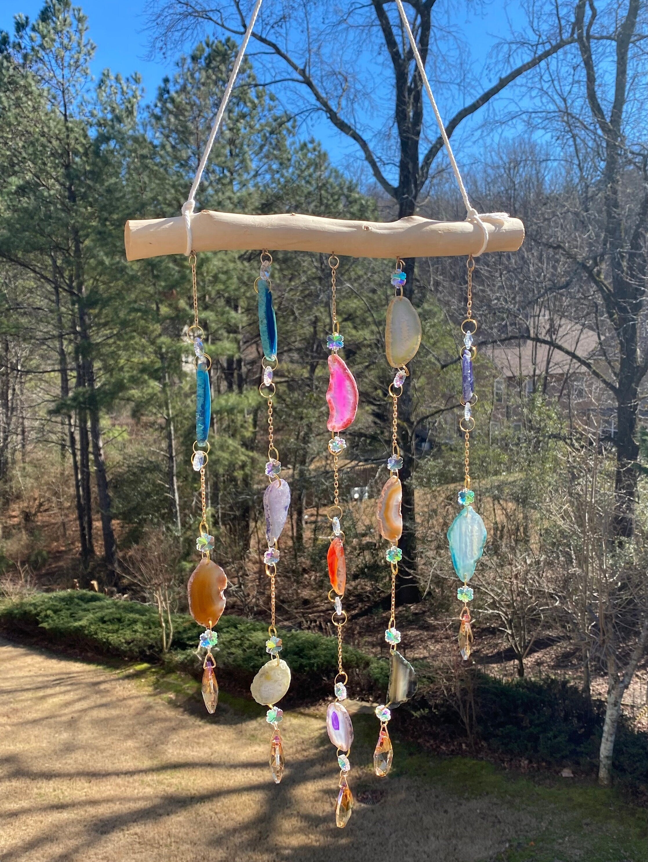 Colorful stone, bead, and crystal wind chime hanging from wood branch decor