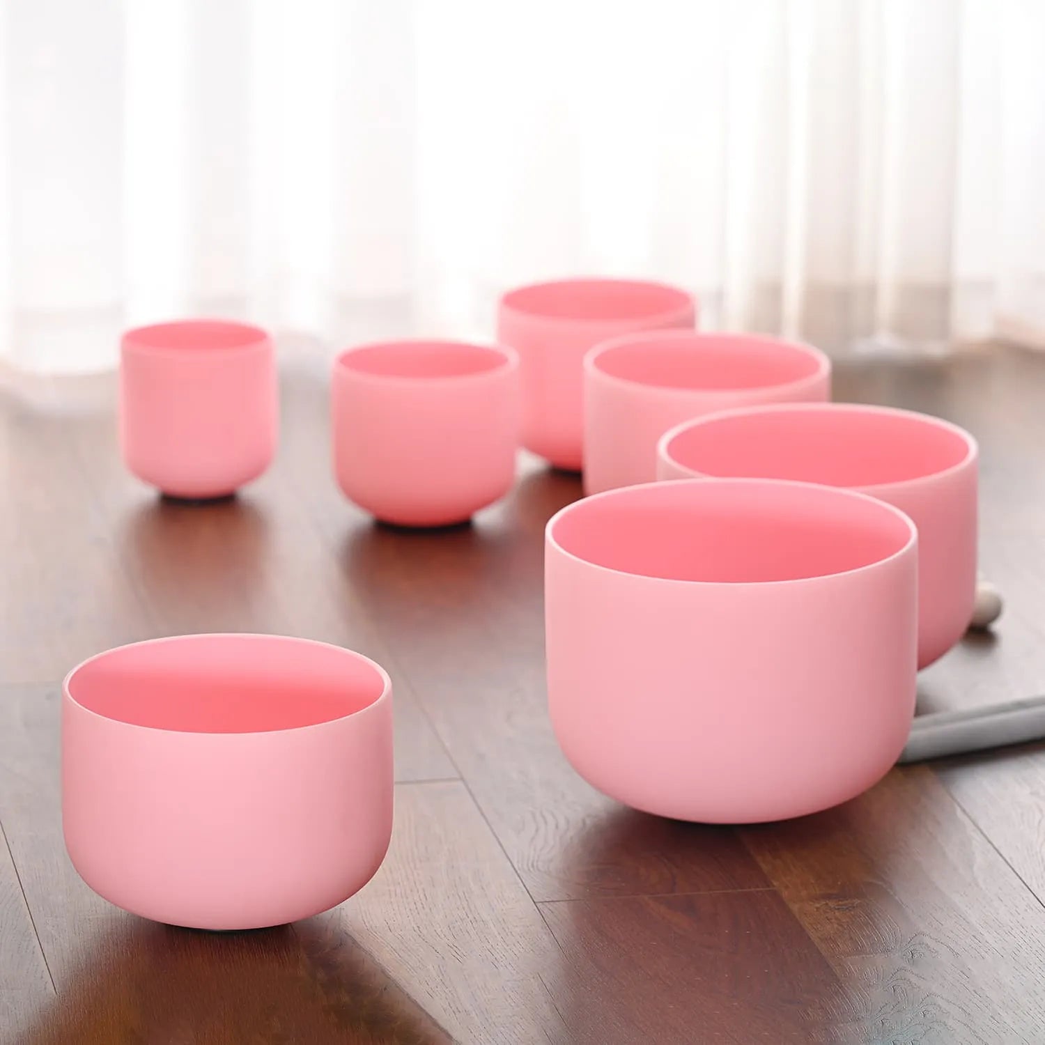 Pink ceramic tea cups in a row with a Pink Frosted Crystal Singing Bowl Set