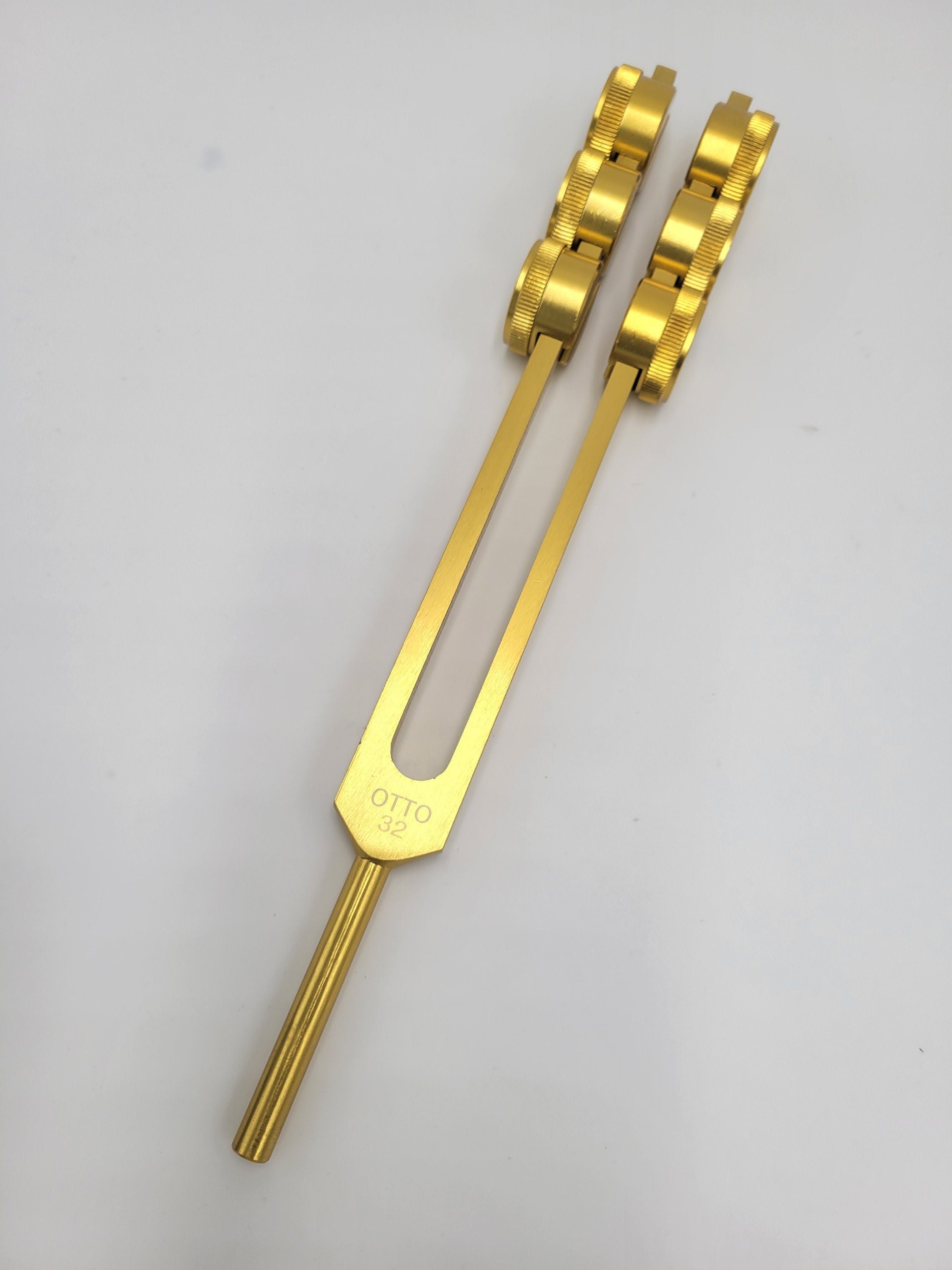 Gold-colored 32 Hz Tuning Fork with dual prongs for healing and sound therapy