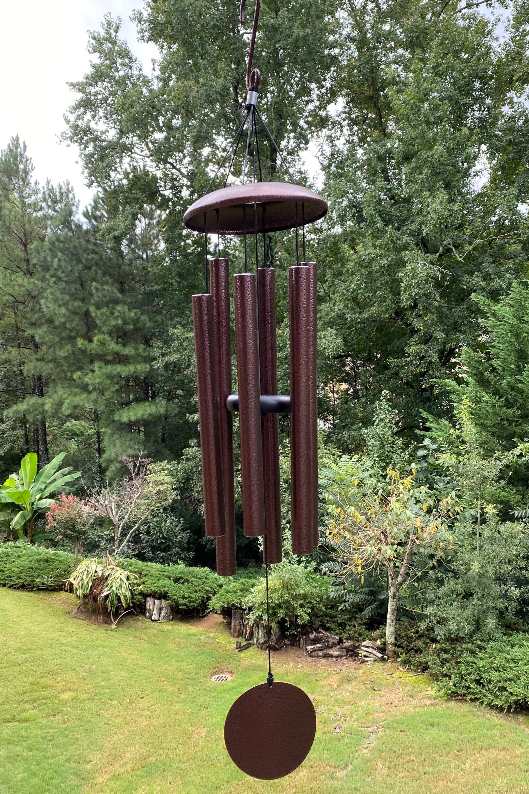 Wind chime with metal tubes and circular base in outdoor setting, 33-48 inch deep tone bronze