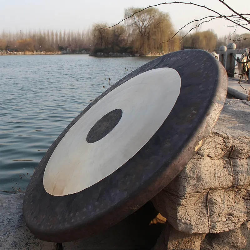 38 Inch Chinese Gong with black edges and white center resting on stone for sound healing