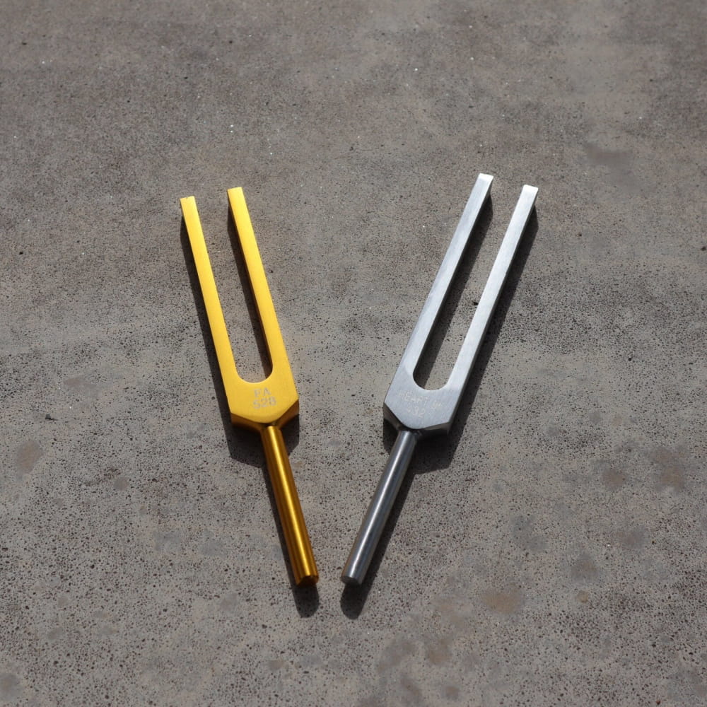 Two tuning forks, one yellow and one silver, for 432 Hz and 528 Hz vibration healing