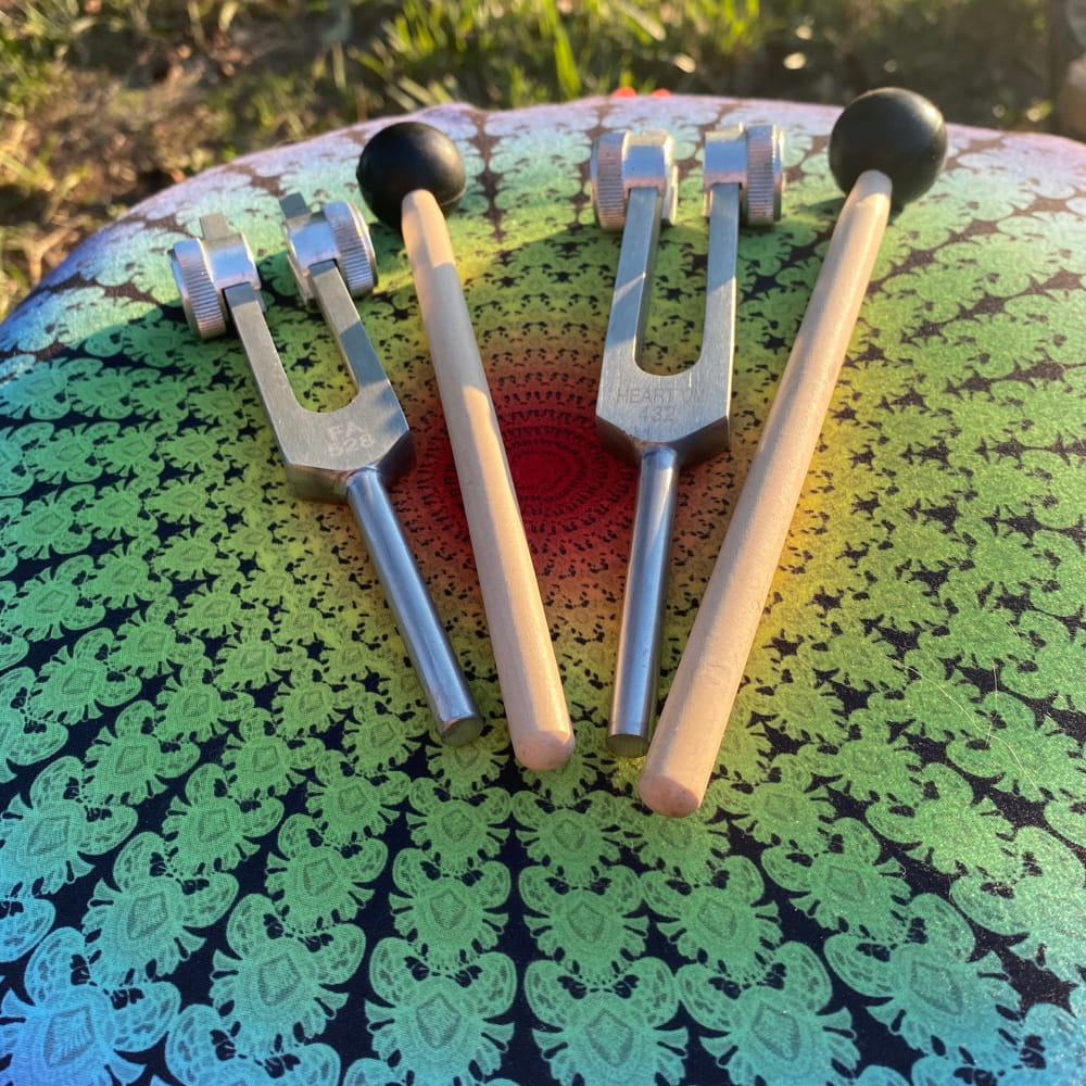 Two Solfeggio Tuning Forks with wooden handles on a patterned surface