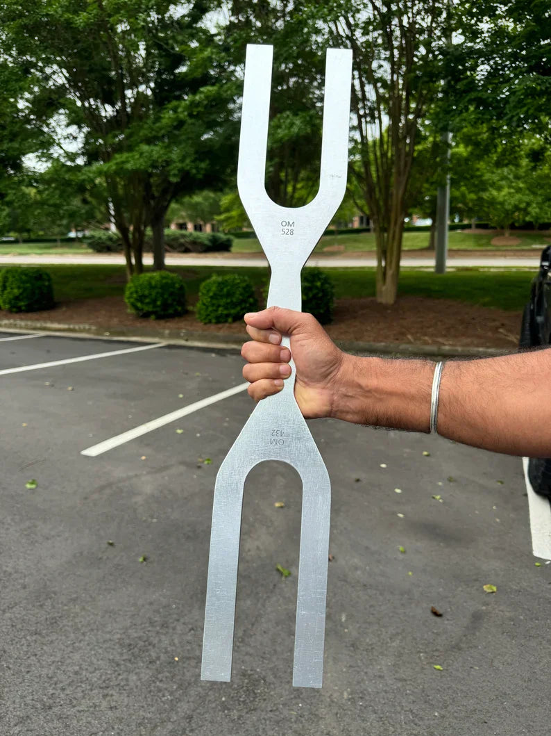 Hand holding a 432 Hz and 528 Hz tuning fork for dual frequency healing