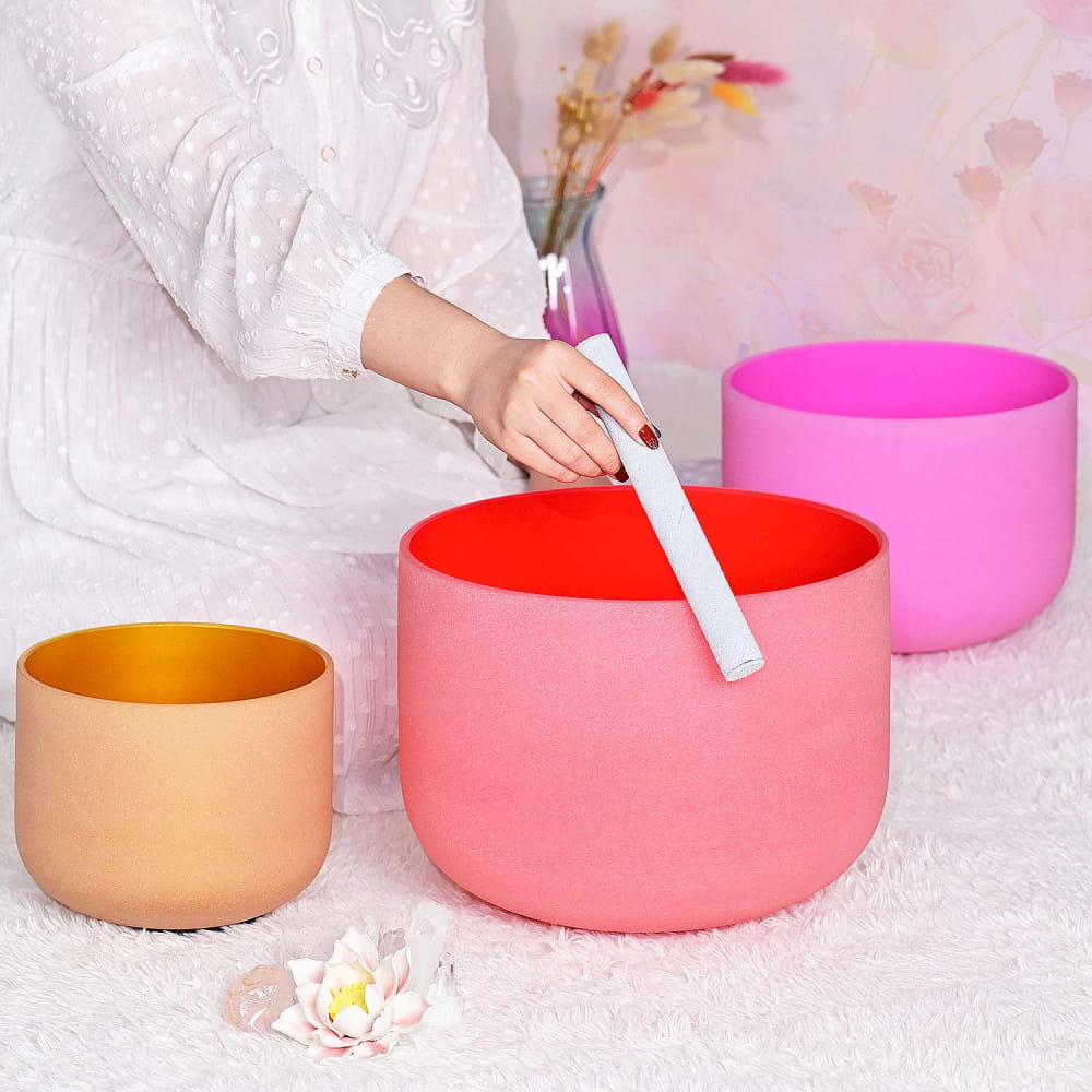 Colorful crystal singing bowls in orange, coral pink, and magenta shades of 432Hz set