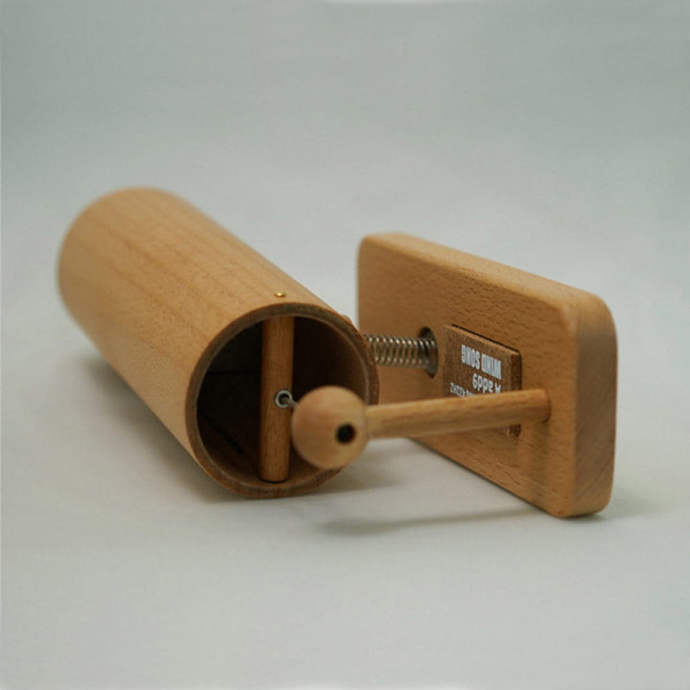 Wooden spice grinder with cylindrical body and rectangular base near Koshi Wind Chime Bell