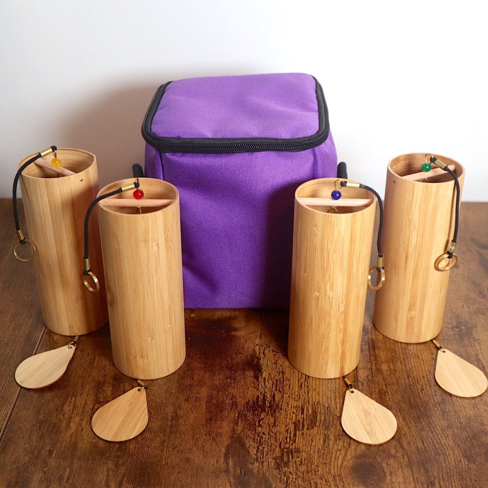 Four bamboo shakers with beaded strings around a purple carrying case for wind chimes