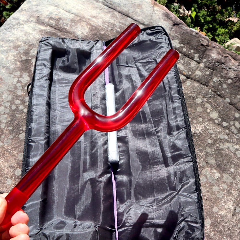 Red tuning fork on dark fabric case for 528Hz sound healing and chakra therapy