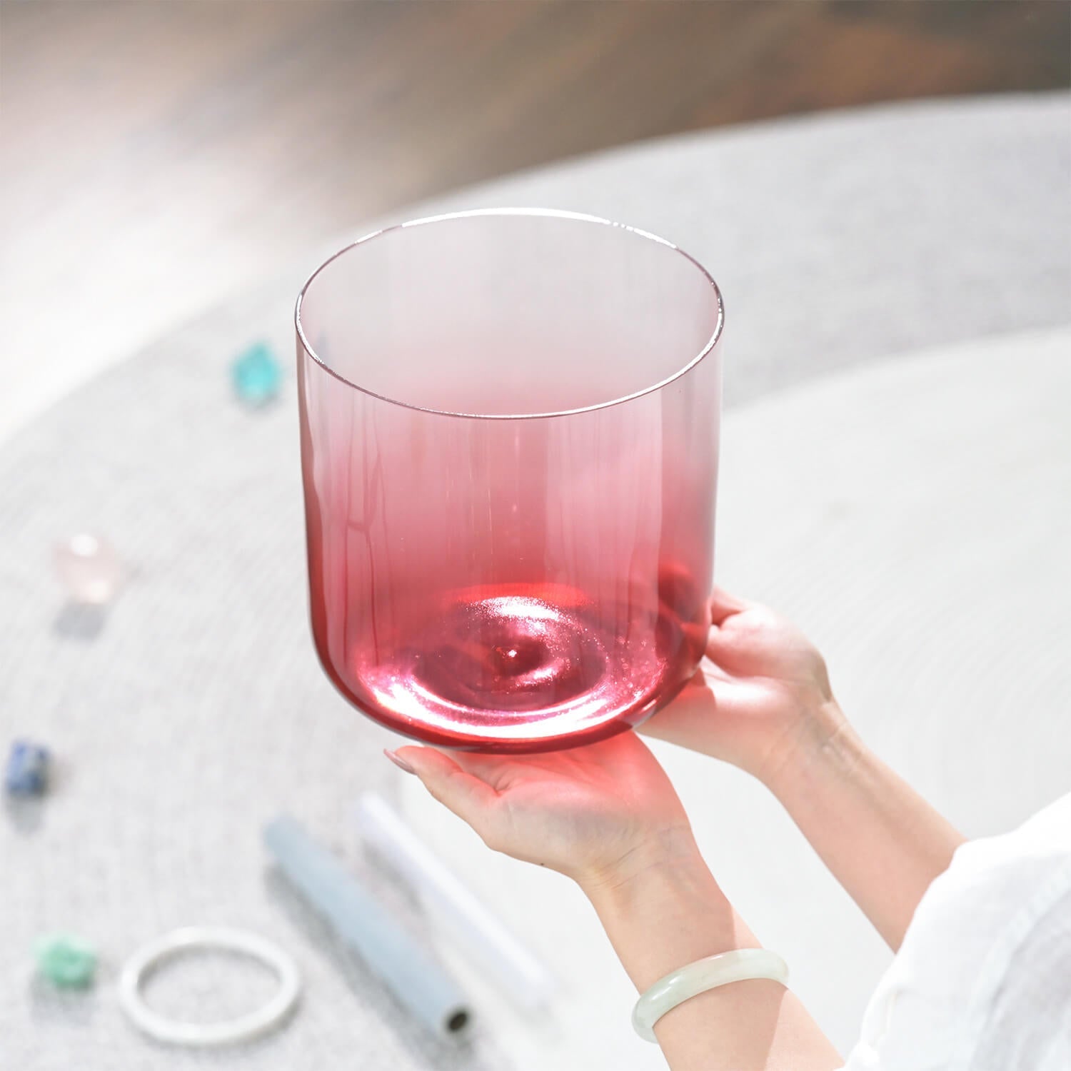 Pink glass tumbler held by hands beside a 6’’-7’’ Crystal Singing Bowl for Meditation Healing