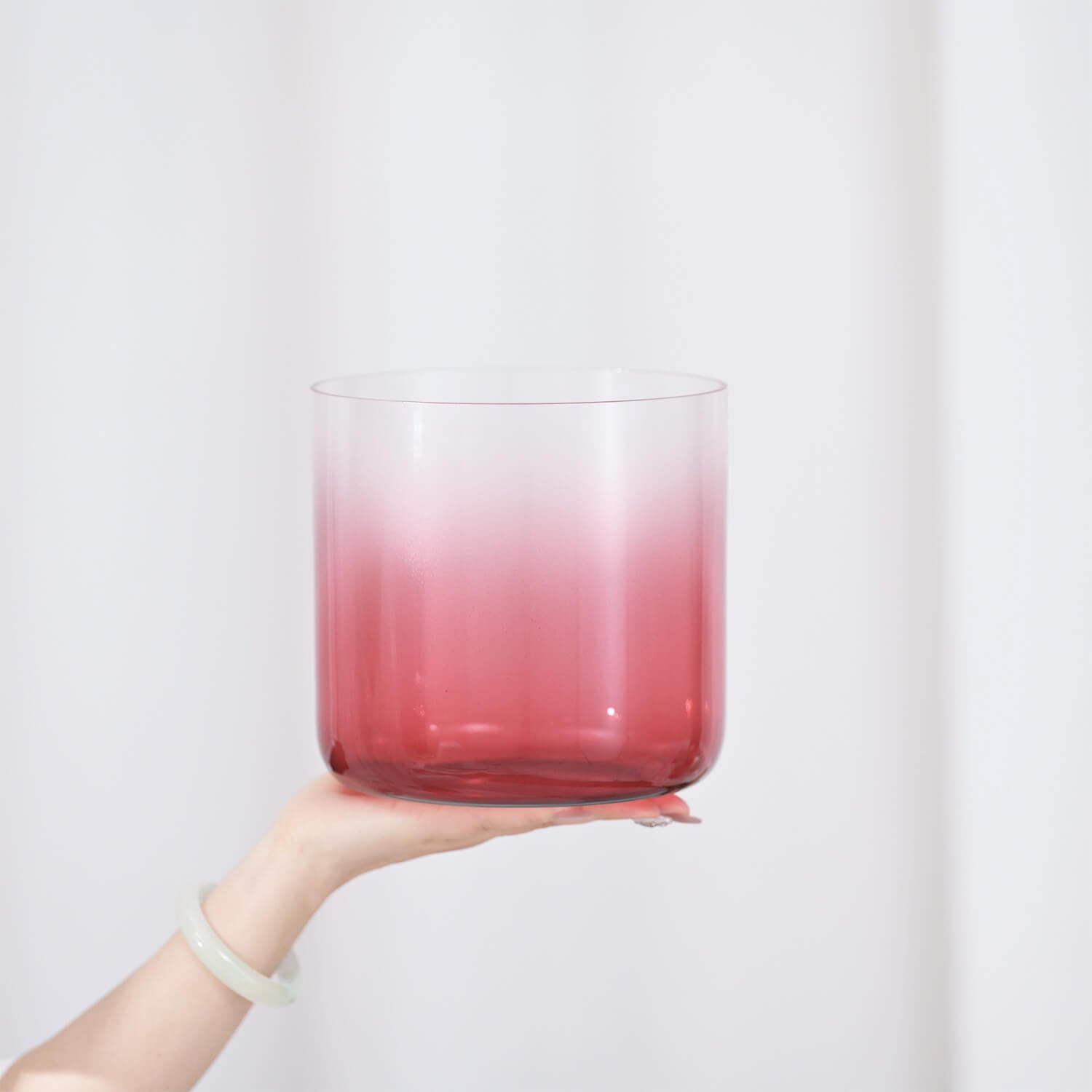 Pink gradient cocktail in rocks glass balanced on hand with Crystal Singing Bowl