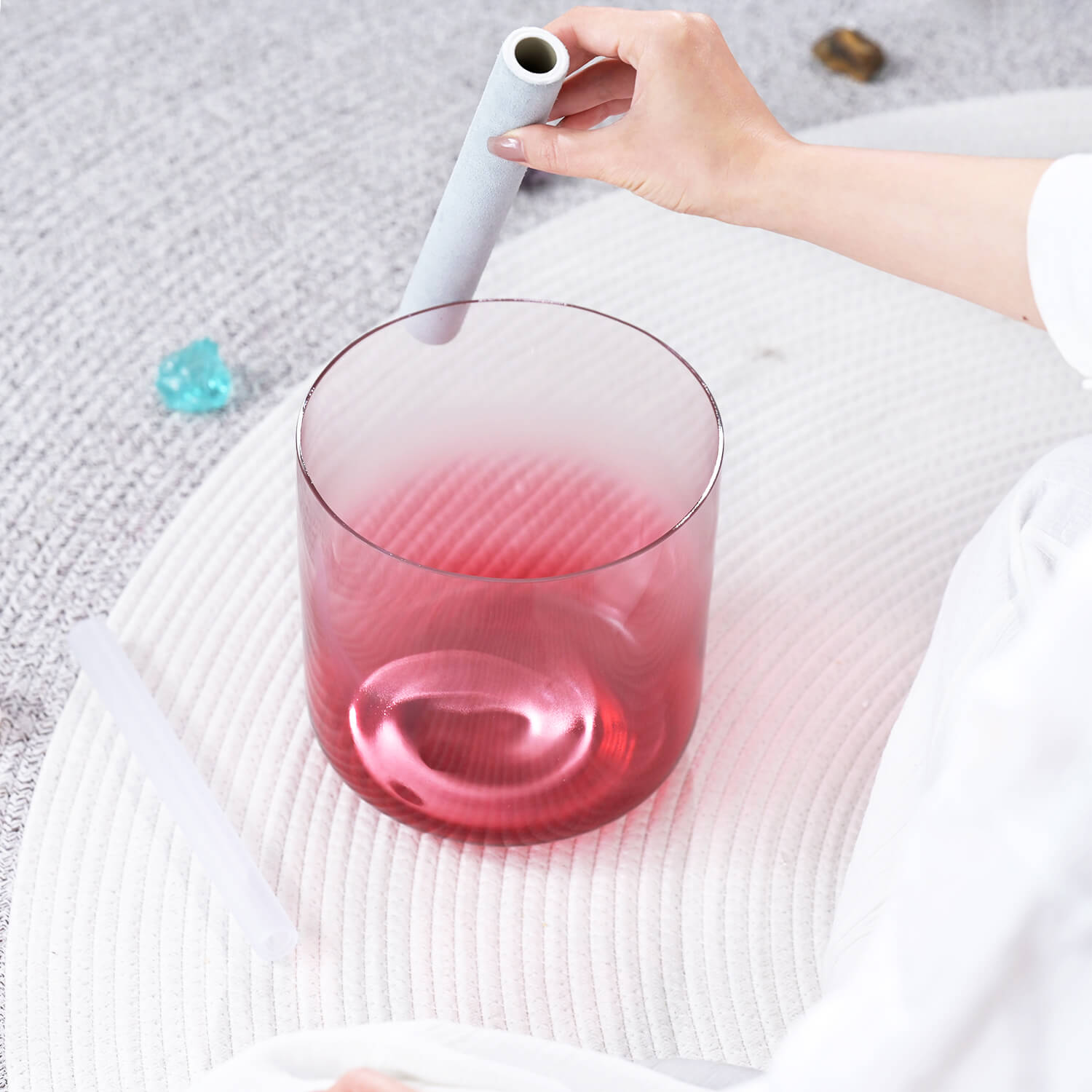 Pink-tinted glass tumbler with liquid being poured for meditation with Crystal Singing Bowl