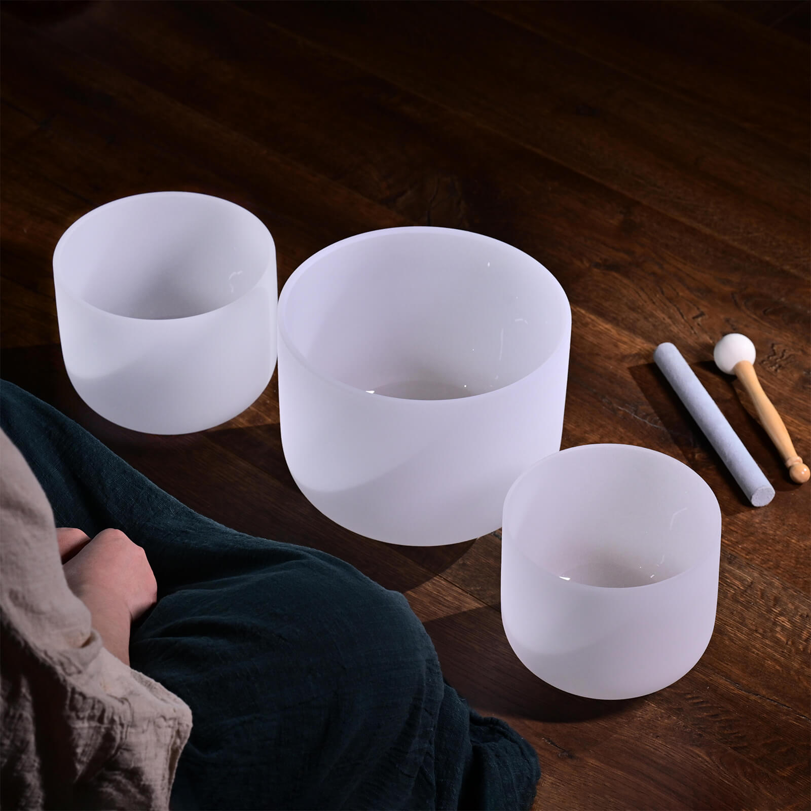 Three frosted white crystal singing bowls with mallets for healing and sound baths